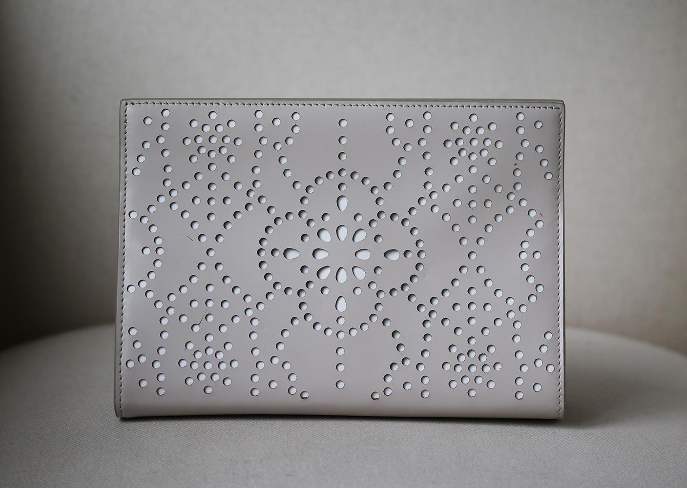 This intricately designed clutch is perfect for a night out. Featuring a neutral pallete of warm grey and white, this laser cut clutch was created to mimic broderie anglaise. The interior is fully lined with leather and comes with a matching vanity