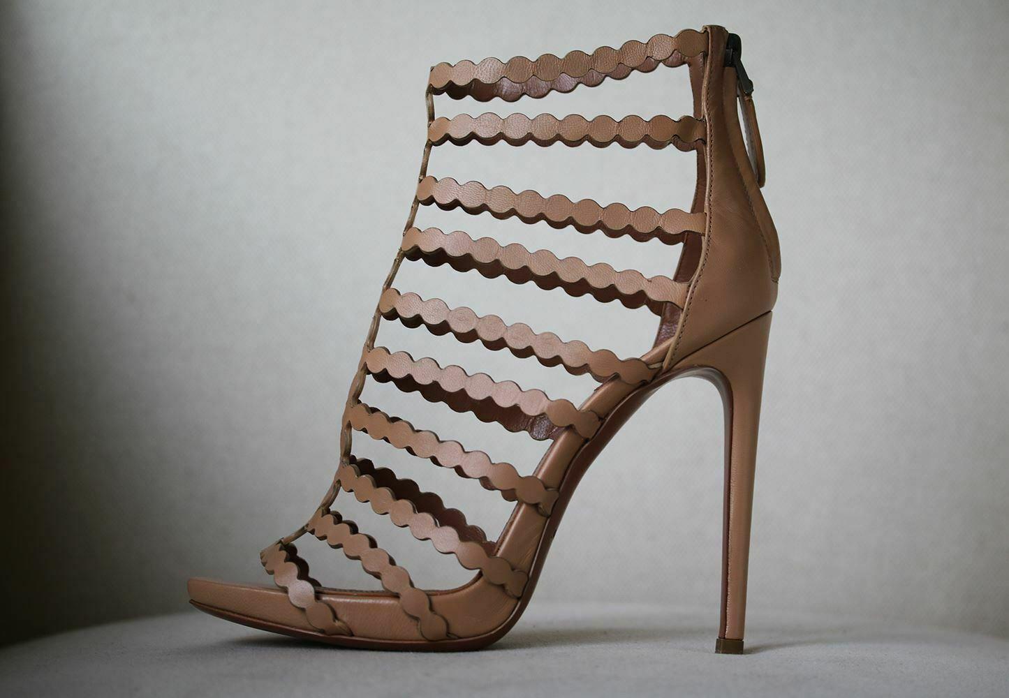 Neutral-hued sandals are supremely versatile. This pair by Alaïa is crafted in Italy using the label's signature laser-cutting technique. Heel measures approximately 115mm/ 4.5 inches with a 20mm/ 1 inch platform. Sand leather. Zip fastening along