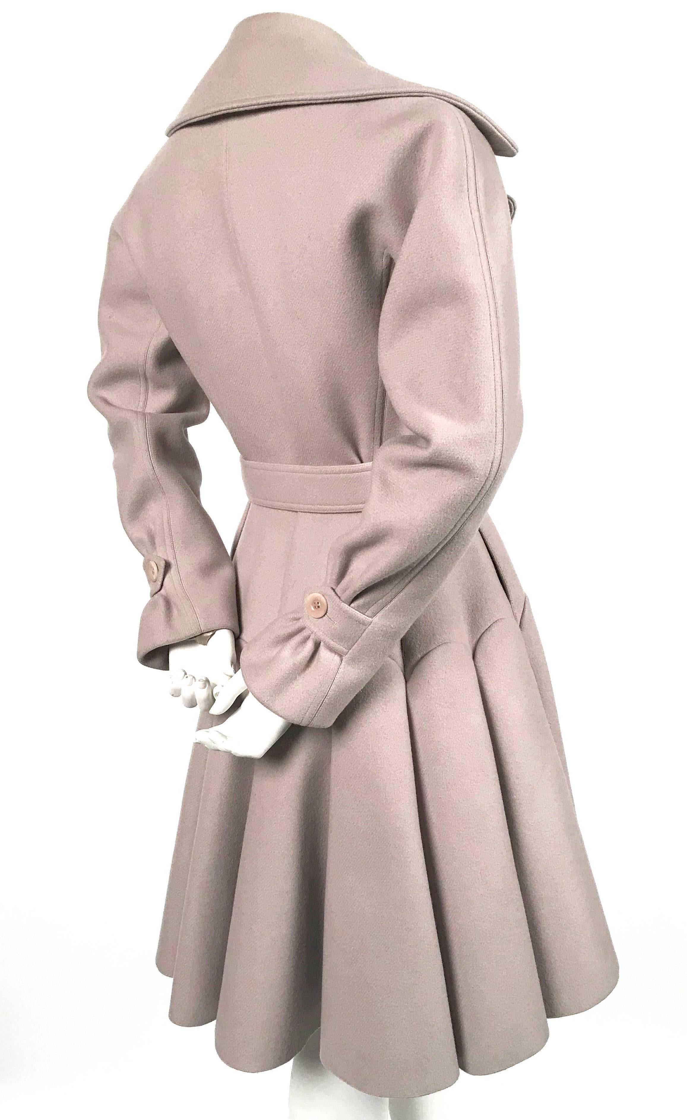 Oyster colored wool coat with notched lapels, seamed skirt and belted waist designed by Azzedine Alaia. French size 40. Approximate measurements: bust 36