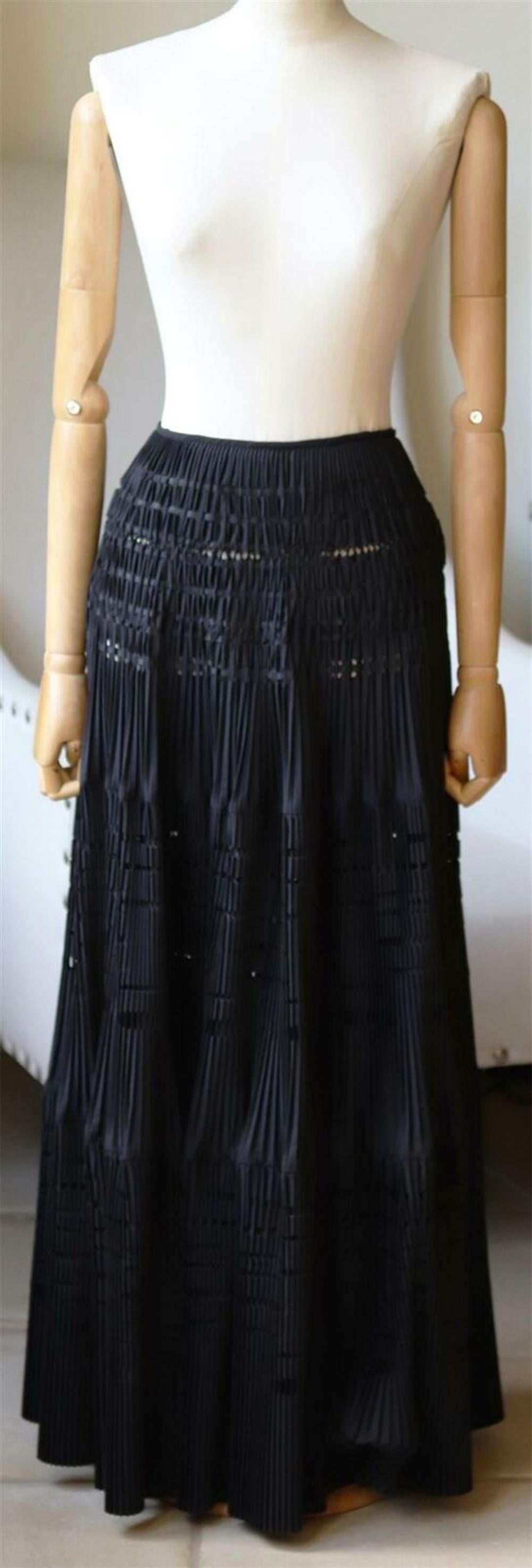 This Alaïa cotton-blend maxi skirt is hand-pleated and laser-cut with geometric perforations.
It is finished with lustrous satin ribbons that are woven into fabric to create a corseted effect at the waist. 
Black cotton-blend.
Concealed hook and zip