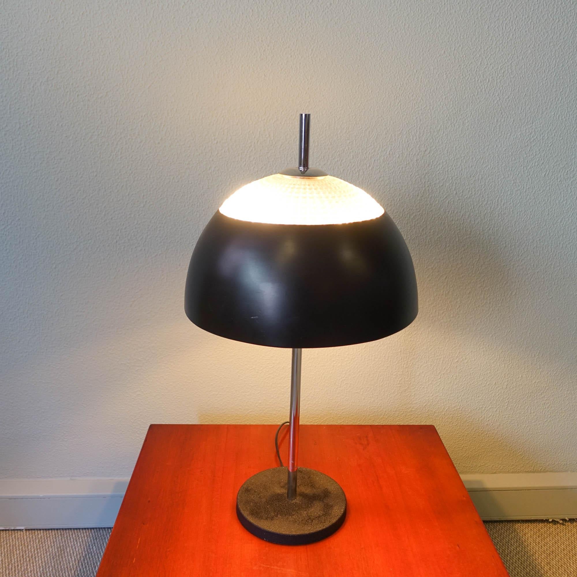 This lamp, model number B-2088, was designed by Frank Ligtelijn and produced by Raak, in Holland during the 1960's. 
The lamp is made of a cast iron round base that has been wrinkle coated in black all around, a solid chromed tube and a shade that