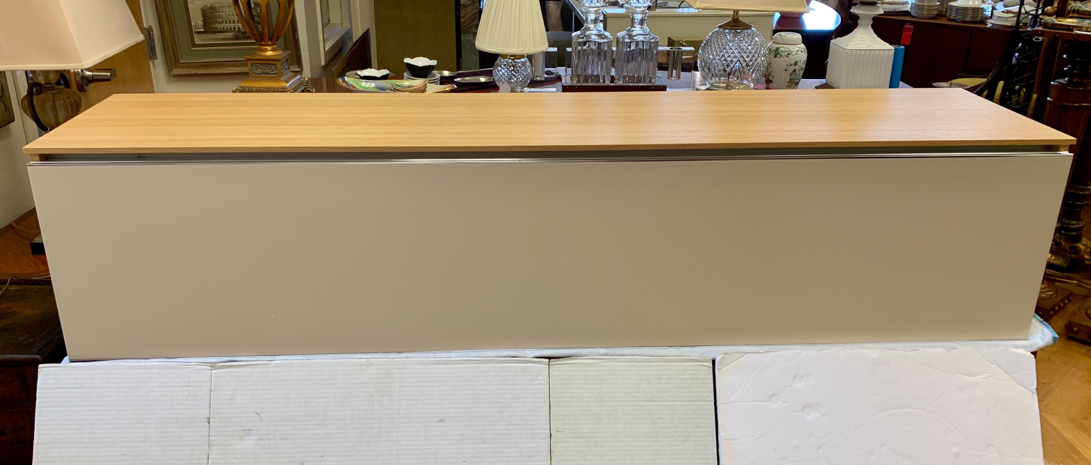 B&B Italia PAB wall system consisting of mounted unit that can be used as a sideboard, credenza or entertainment console. Two front doors open and fold down to storage. The frame and top are in a light oak finish. The doors are in a light beige