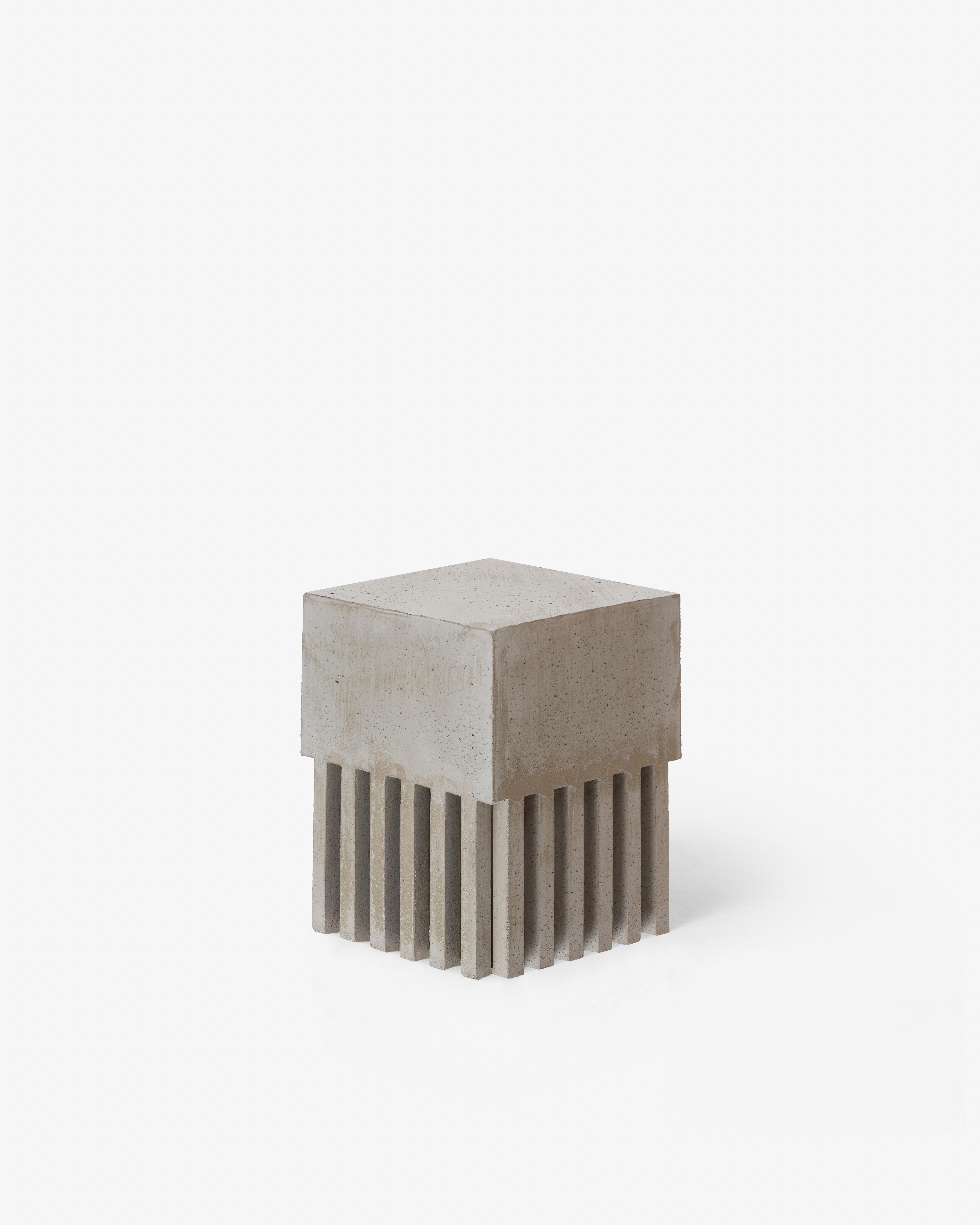 This monolithic concrete table emphasizes sculptural geometry and presence. Vertical striped bases lift the mass,
adding rhythm and lightness to its volume. Referencing Brutalist architecture and minimalist sculpture, it functions as
table, plinth,