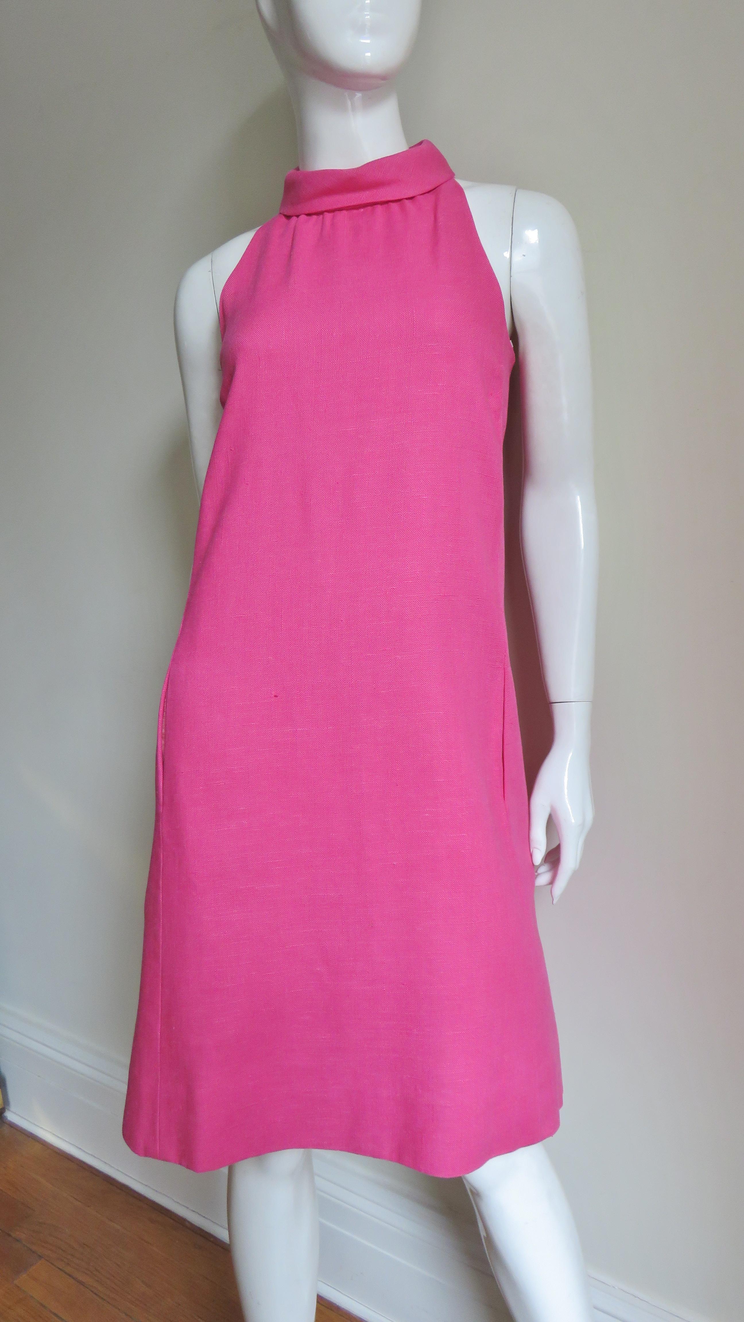 A great bight pink mid weight linen dress from B. H. Wragge (specifically the year 1967 as per the label). It is sleeveless with a rolled collar and it flares subtly to the hem.  The back has a large oval cutout and closes with 3 self covered