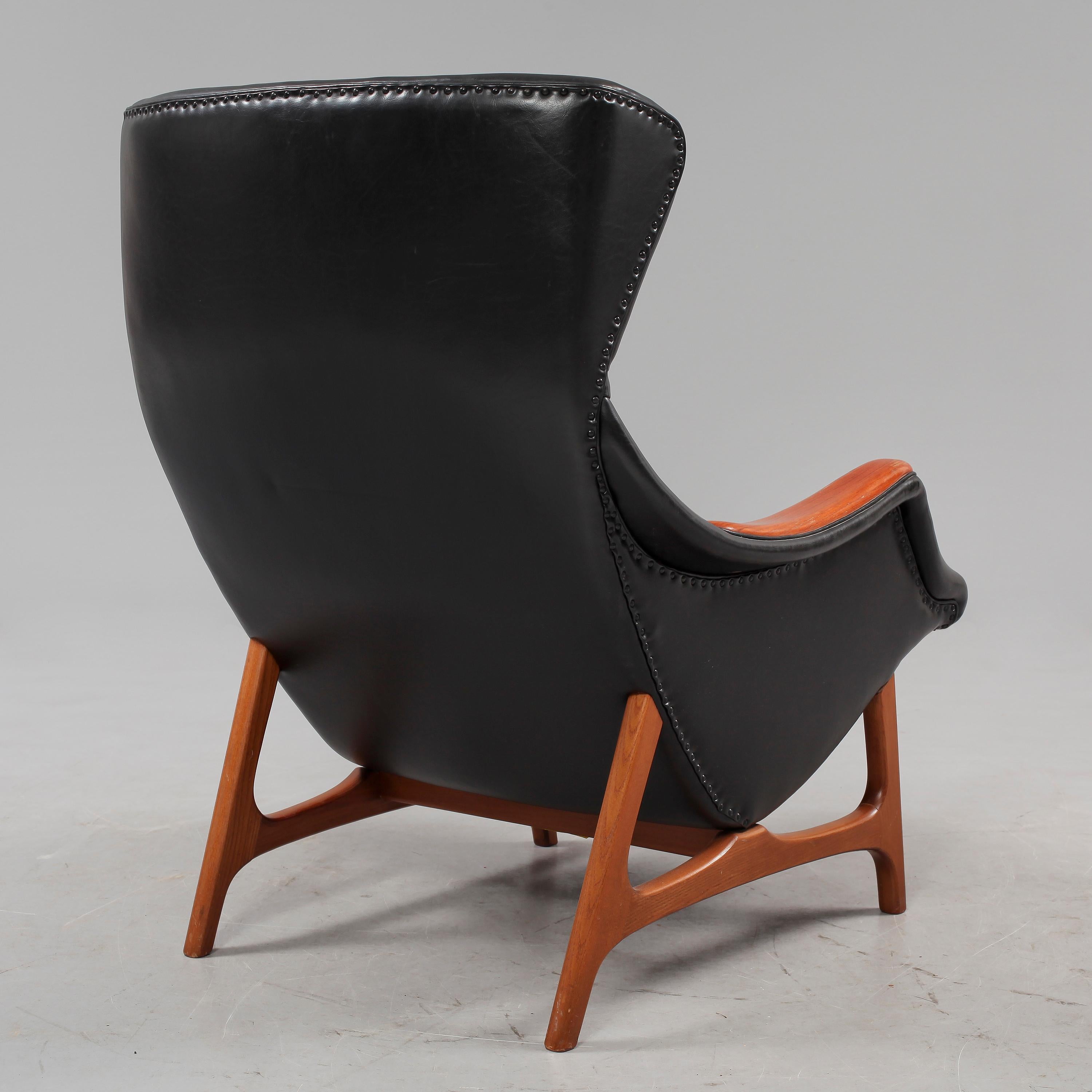 lounge chair designed by B J Hansen made in Norway around  1960.
Lounge chair + side table that becomes a footstool when the top is turned upside down. Draft 1960s. Teak, black synthetic leather. Armchair: 95 x 73 x 89 cm. Stool: 39 x 65 x 48