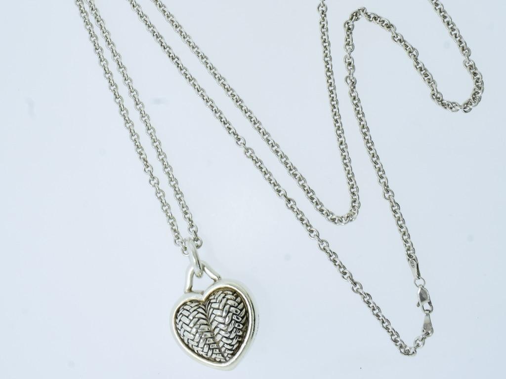 A woven or thatched design is done on both sides of this sterling silver heart which is suspended from a long cable link sterling silver chain.  The heart is signed B. Kieselstein-Cord, 1996, with his mark of the new moon and 5 point star, followed