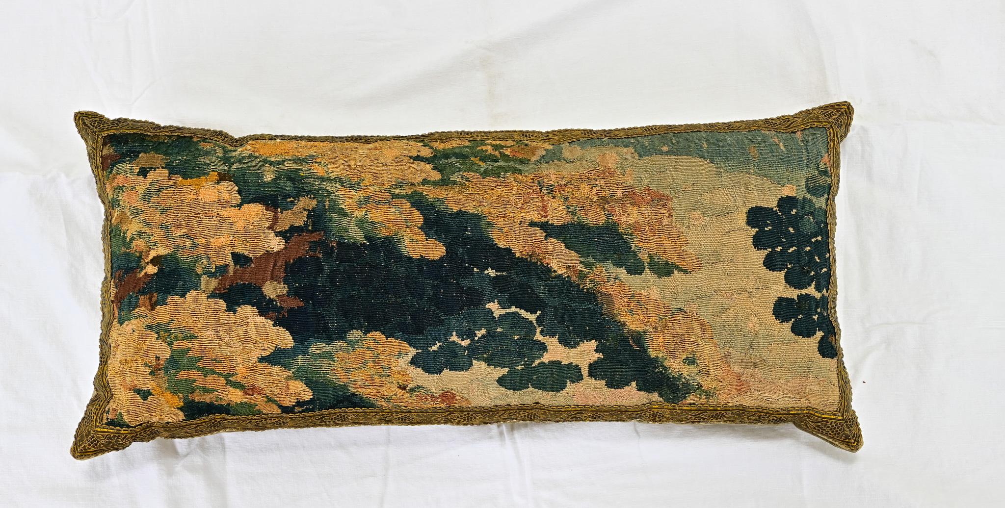 A single 19th century tapestry fragment and brass velvet pillow, designed by Rebecca Vizard for B. Viz Design. This down filled pillow makes a statement with a 19th century tapestry fragment depicting flora and sky in shades of gold, brown, blue,