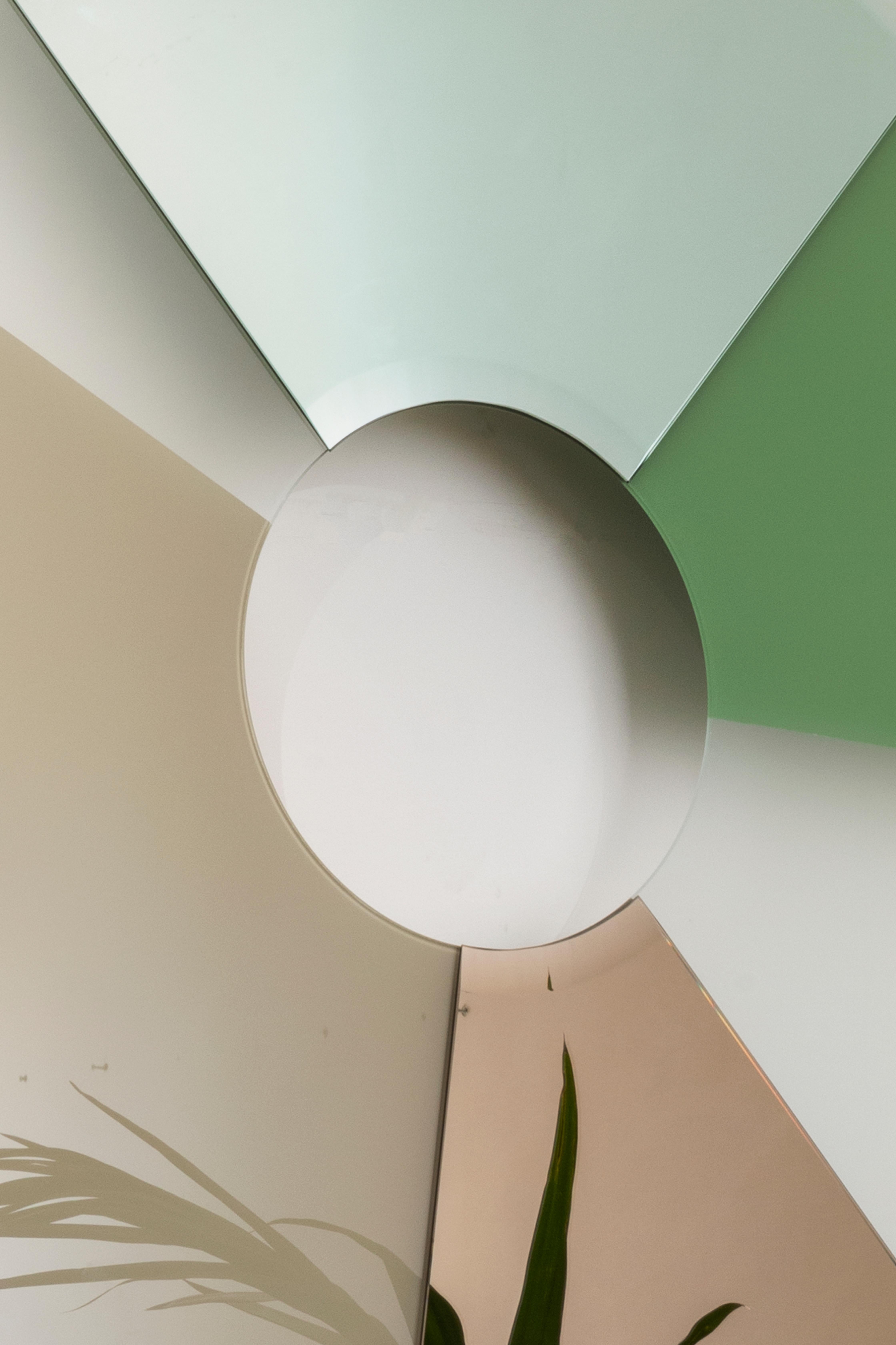 Taking inspiration from the chromatic circle and its circular representation of colors, Boom has alternating sections of satin lacquered glass and colored mirrors. The frosted glass surface, a few centimeters away from the wall, reveals the shadows