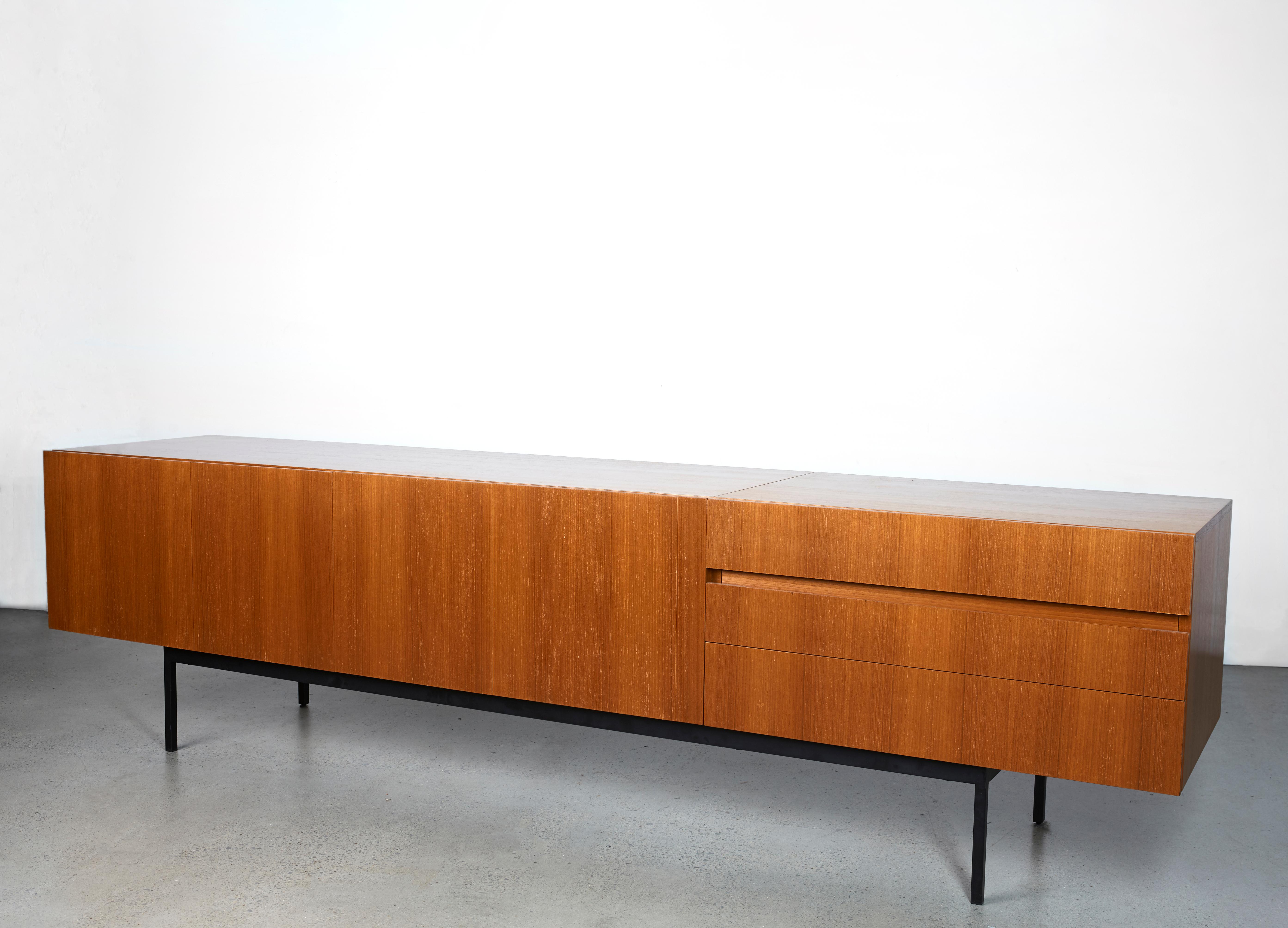 This low teak sideboard, model 'B40', was designed by Dieter Waeckerlin for Behr in a minimalist mid-century style. This piece of furniture with teak on the outside and maple wood/beech on the inside sits on a solid black metal base. It features a