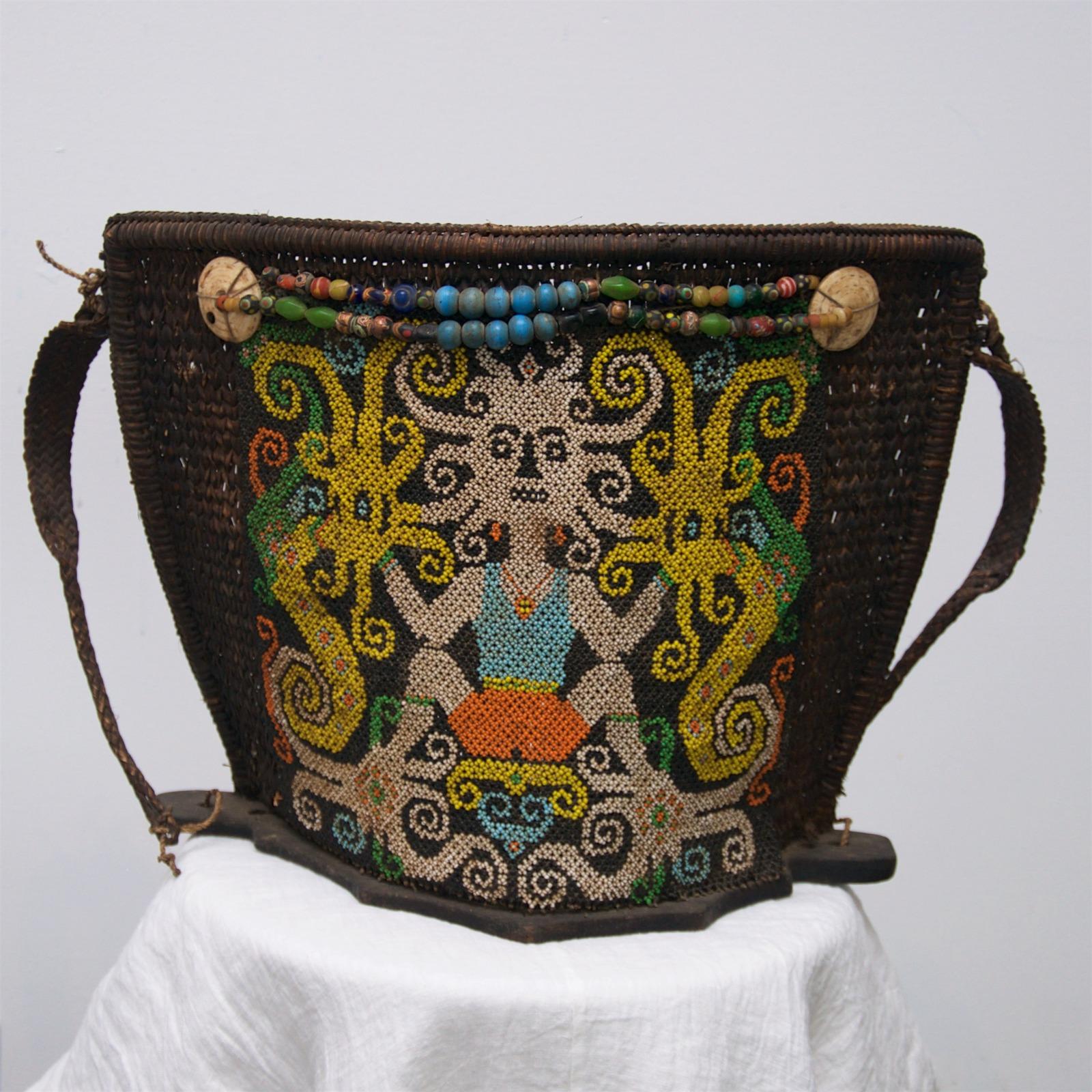 Dayak baby carrier from Borneo, Indonesia, estimated made in mid 1900’s. Colourful bead work depicting tradition mother goddess hand-stitched on rattan grass basket with two shoulder straps. Base is wood. Decorative and valuable bead used to