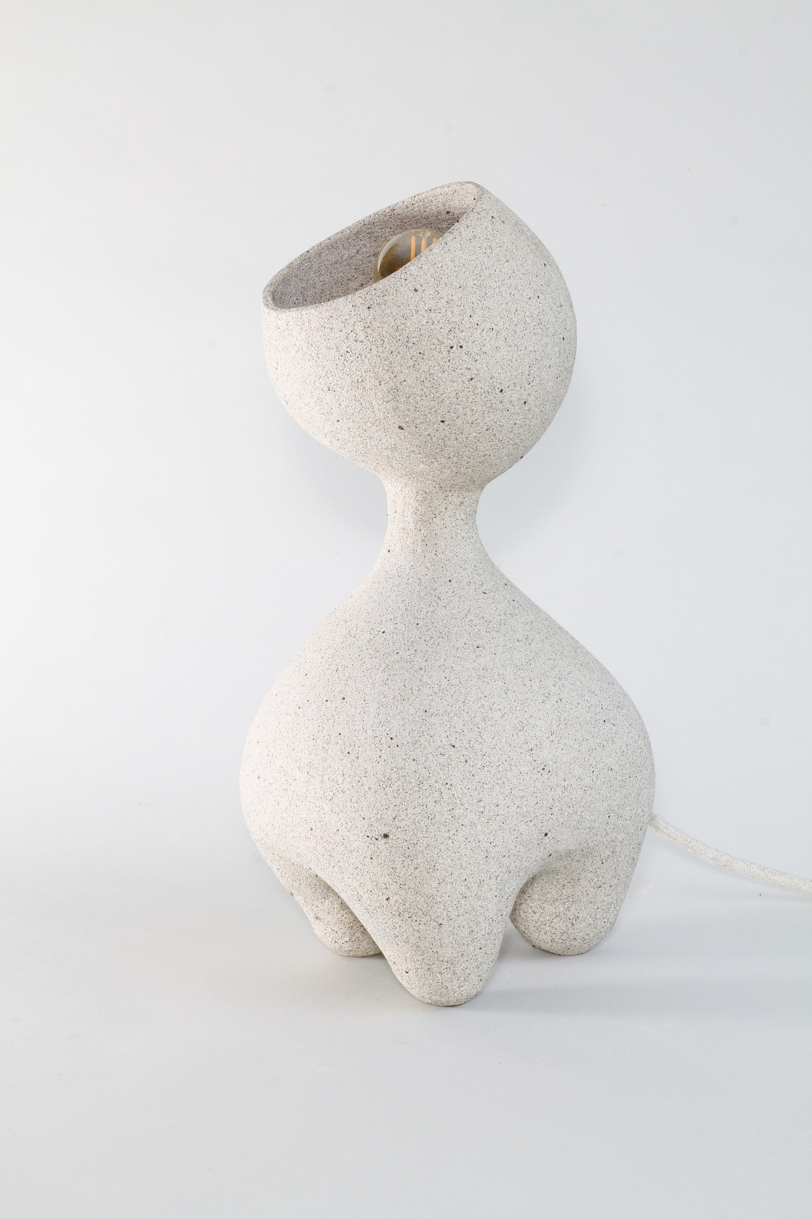 Kerry Hastings a fabriqué à la main cette lampe de table unique en céramique dans une argile de grès à laquelle elle a ajouté du sable volcanique noir pour obtenir un mouchetage distinctif semblable à de la pierre sur toute la pièce.  Inspirée par