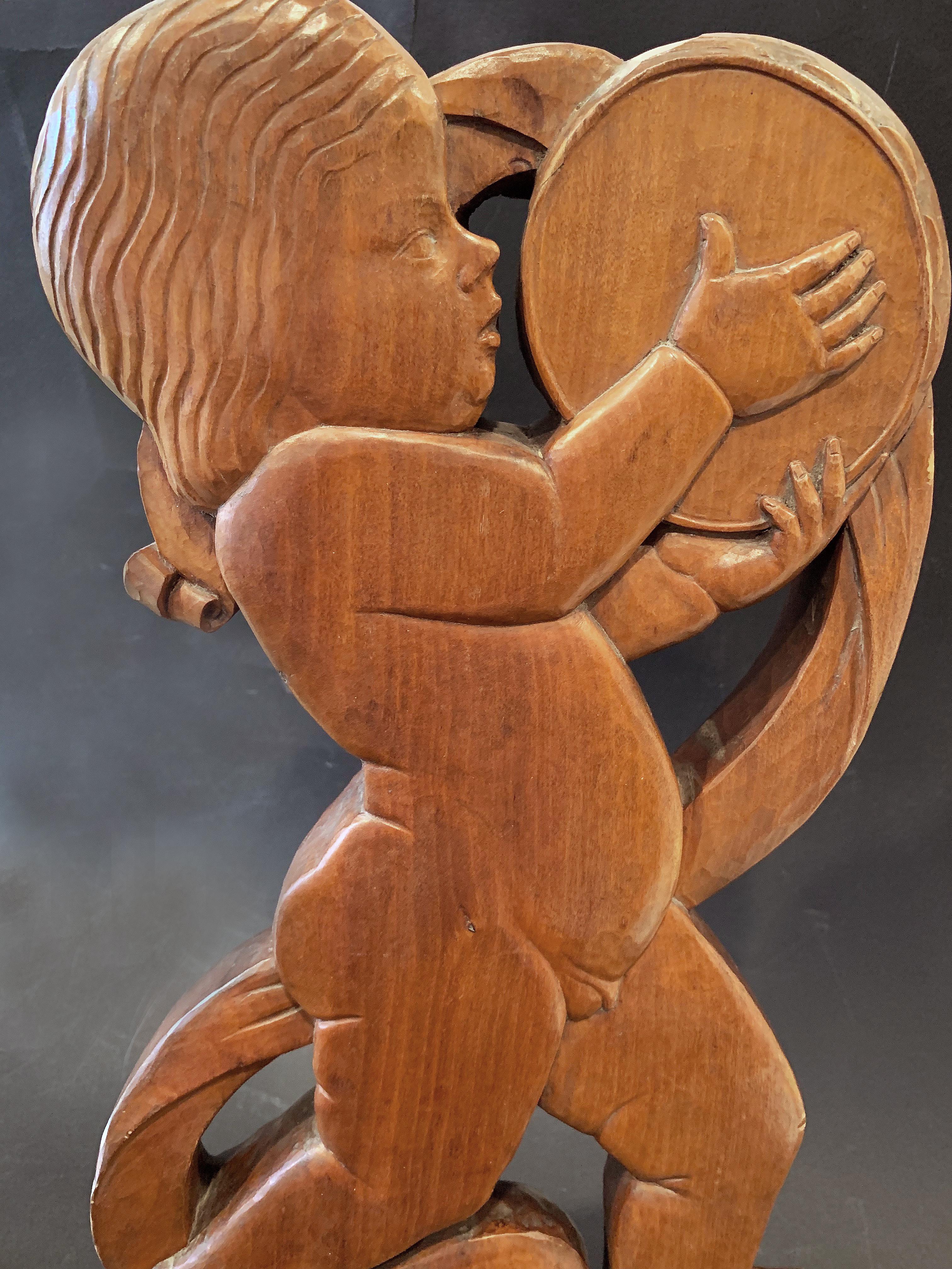 Clearly carved by a master, this spirited and subtle sculpture of a striding baby boy hitting a tambourine and encircled by a winding scroll is a very fine example of Art Deco hand-carving. Sculpted from a beautiful block of American walnut, the
