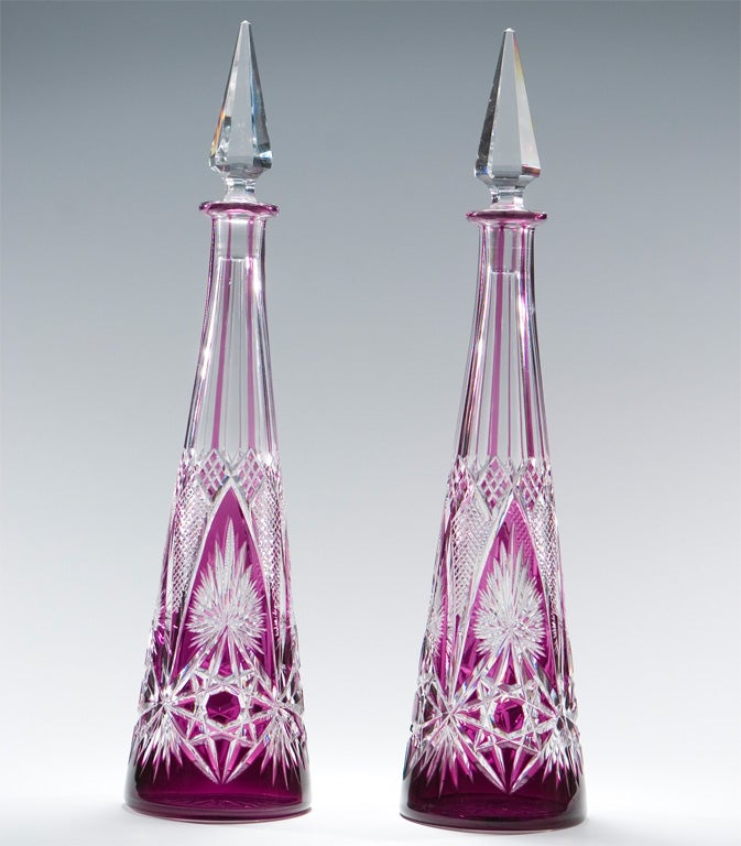 Beautiful hand blown crystal decanter made by Baccarat with amethyst overlay cut to clear. Intricate diamond point cutting over rich jewel-tone amethyst crystal, ready to sparkle on your back bar. Perfectly fitting pyramid cut stoppers add height to