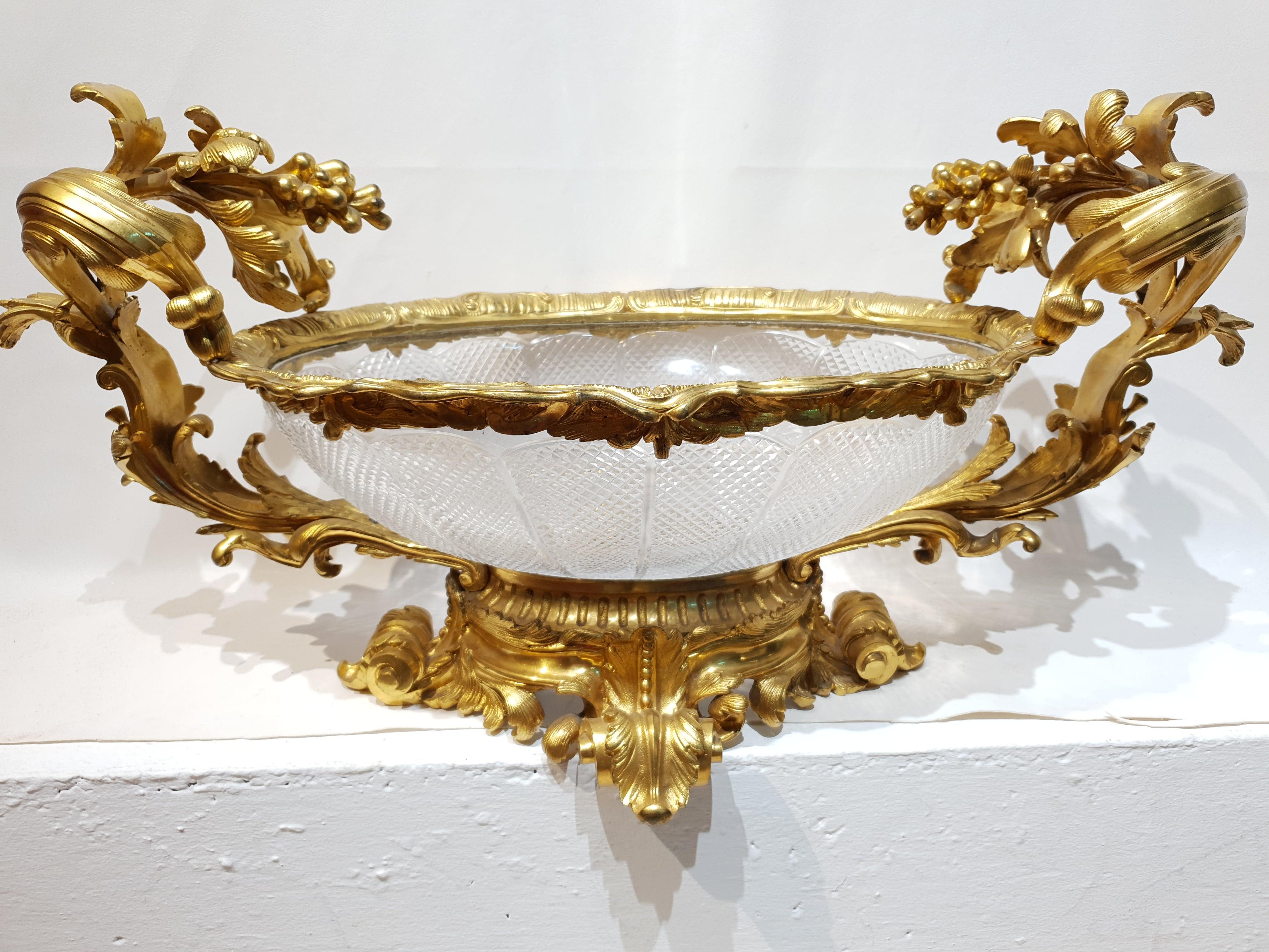 This mid 19th century centrepiece was crafted by the Baccarat French company and is wrought from crystal and ormolu. Ormolu adorns the rim of the bowl and at each sides the handles are in the form of scrolled leaves and grapes. The crystal body is
