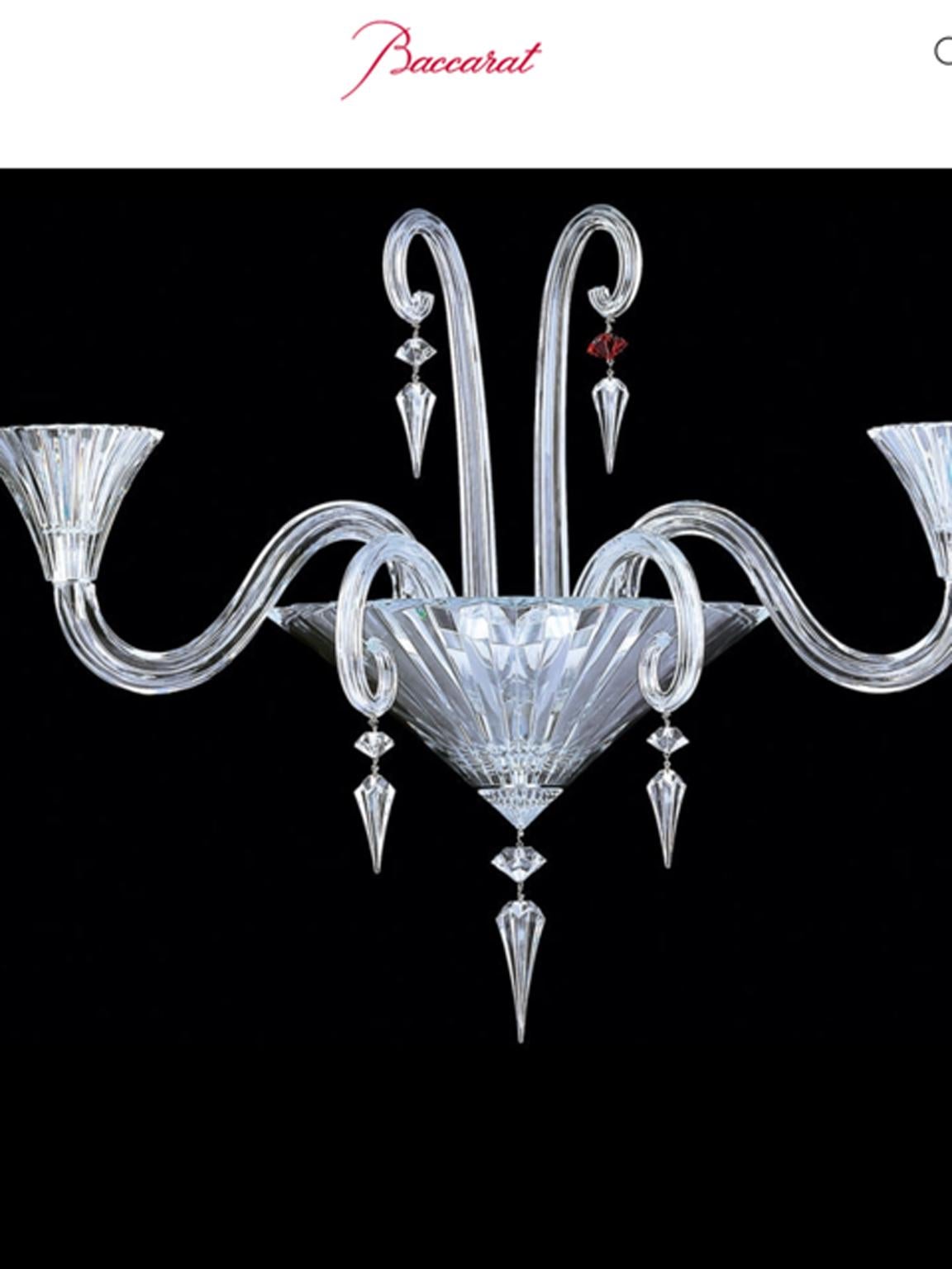 Le perle ornamentali di forma esagonale prismatica, tra le quali spicca il singolo cristallo rosso della firma Baccarat, pendono in abbondanza e si riflettono riccamente.