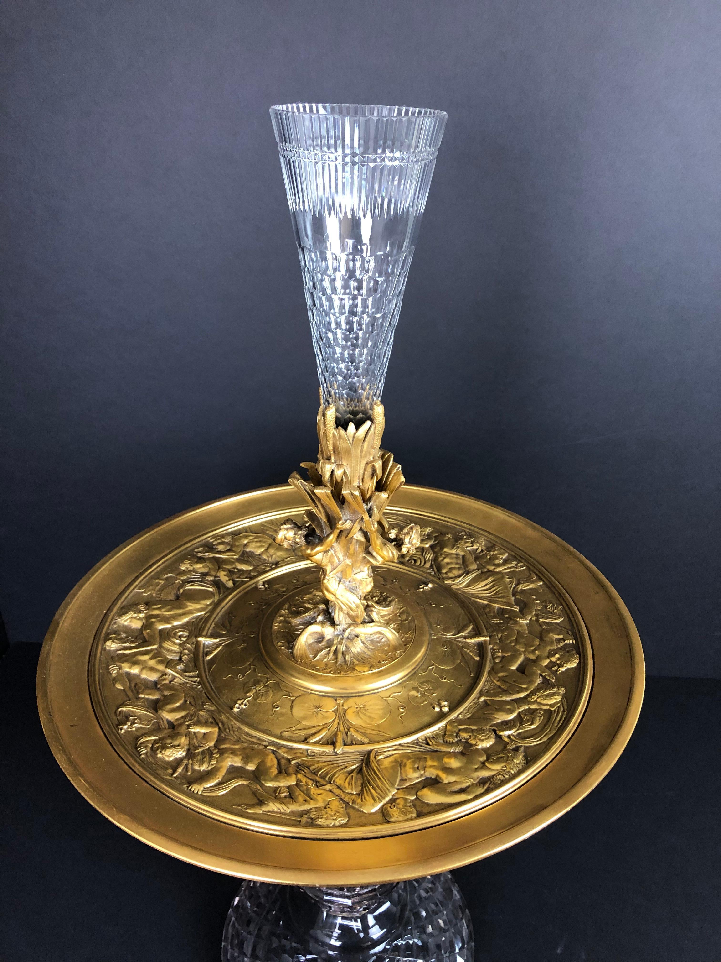 Centerpiece epergne of gilt bronze and crystal. Gilt figural bronze mounted Baccarat crystal centerpiece. Triton figures and sea grass supporting crystal flute. Gilt bronze tazza form charger dish with mythological figures throughout.
Base width