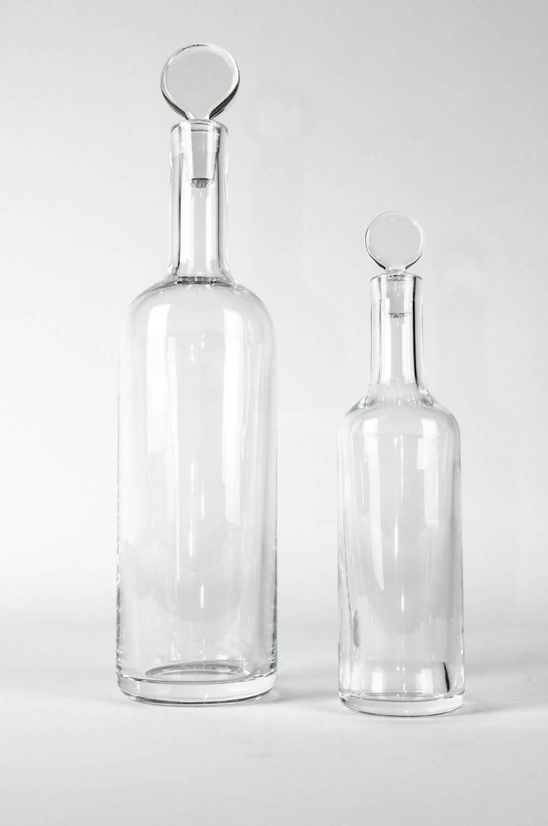 Mid-Century Modern pair of Baccarat crystal Art Deco style wine decanter with flat circular stopper. A seamless design mimicking the shape of a wine bottle makes this a perfect addition to any barware collection. The taller one measure 14