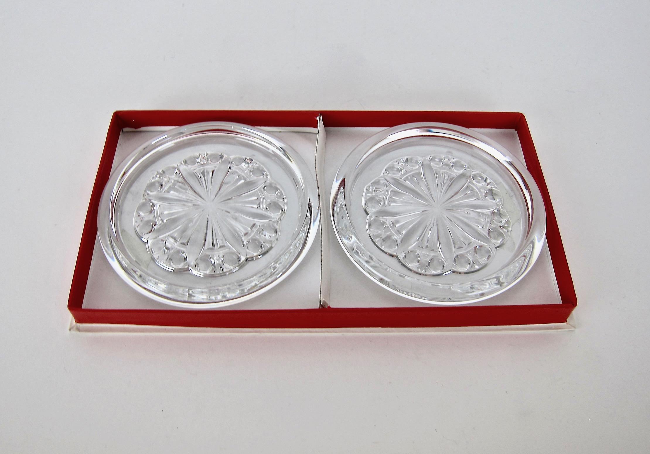 A boxed pair of French Baccarat crystal bottle coasters from the discontinued Rosace line. Each round and colorless crystal coaster is designed to accommodate a large, magnum size bottle of wine or champagne but can also be used as a decanter stand