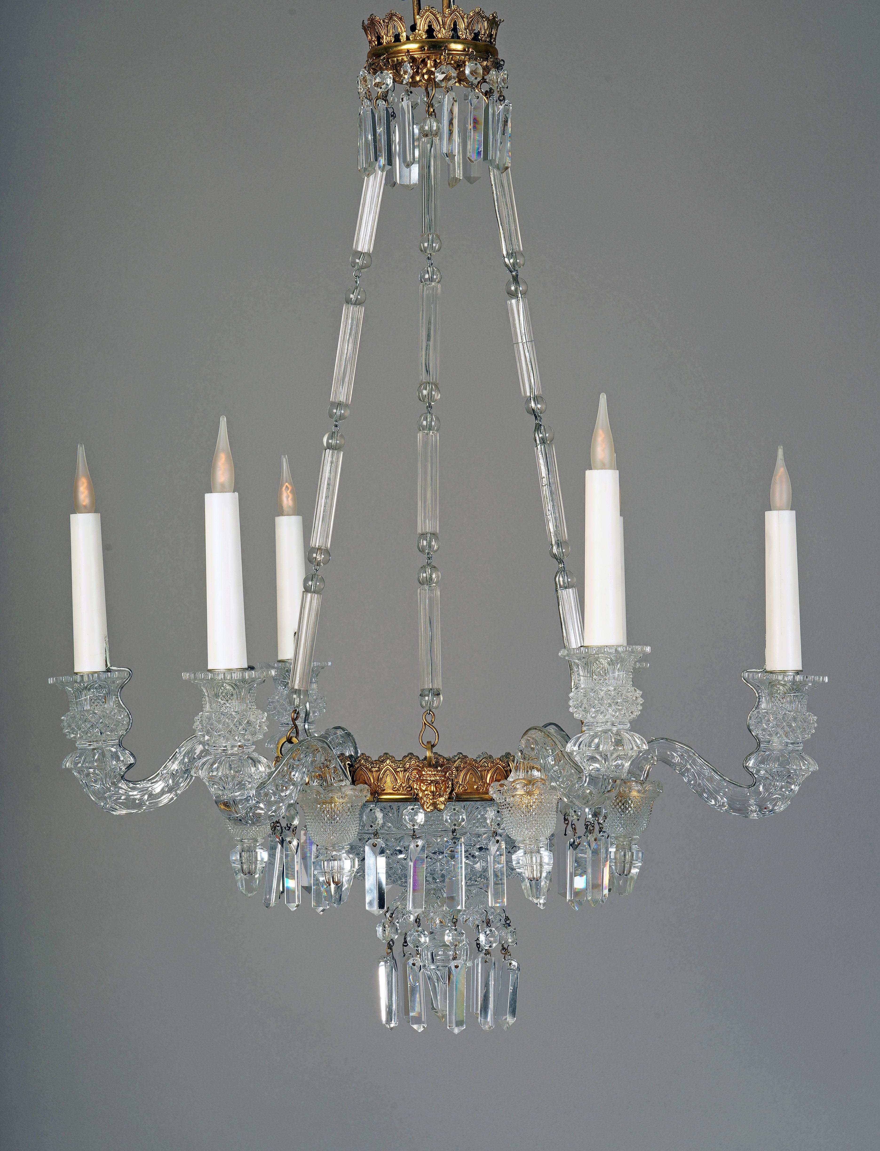Elegant cut and faceted crystal chandelier with six lights. Composed of a cup decorated with palmets on a grid background surrounded by a gilded bronze crown with alternating decoration of flowers and faun’s heads on a leafy background. The set is
