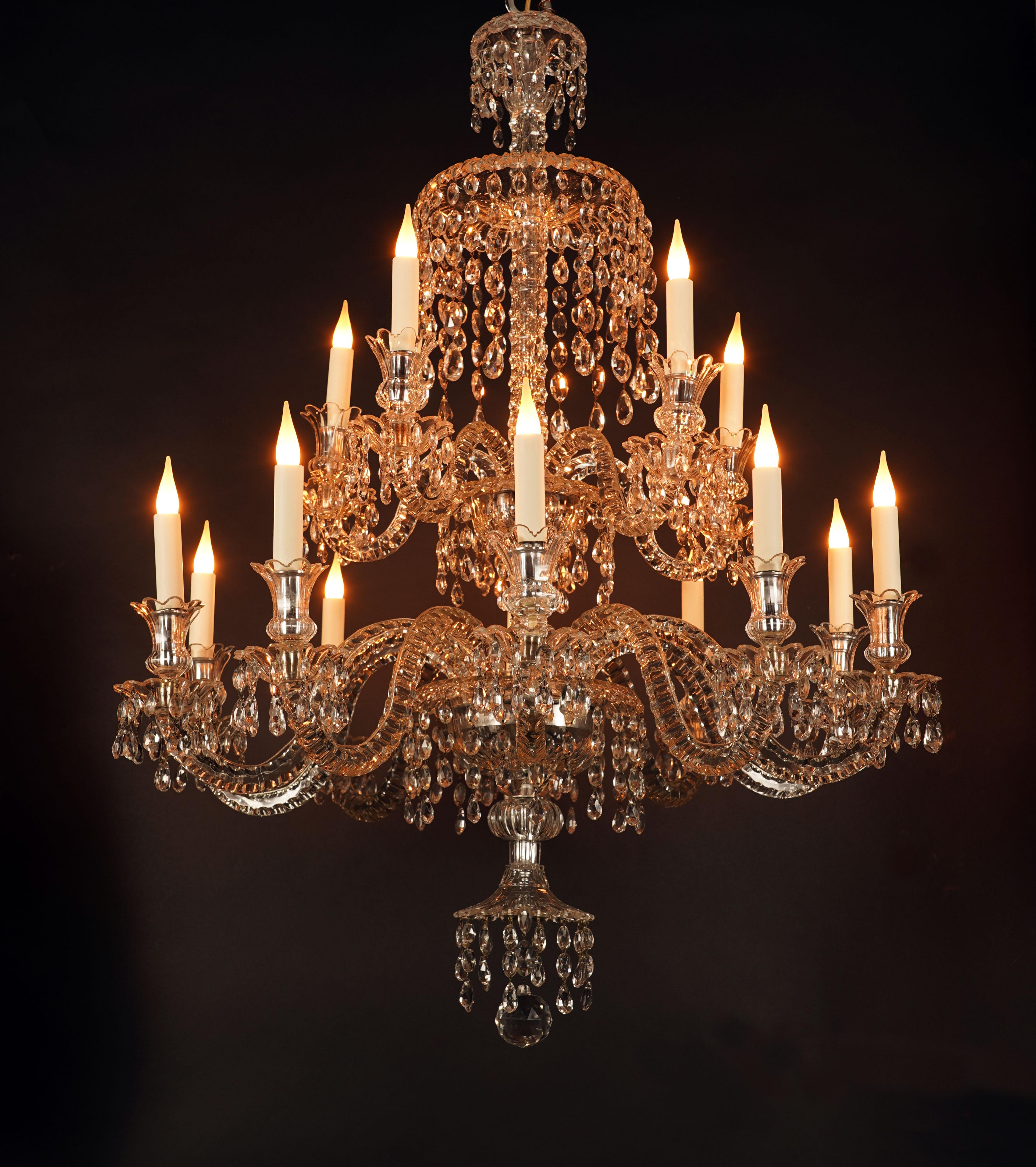 Bellissimo lampadario in cristallo tagliato con quindici luci. Il fusto centrale, decorato con coppe da cui fuoriescono pendenti, presenta due file di cinque e dieci bracci luminosi con rami sagomati e attorcigliati. L'insieme è ornato da numerosi