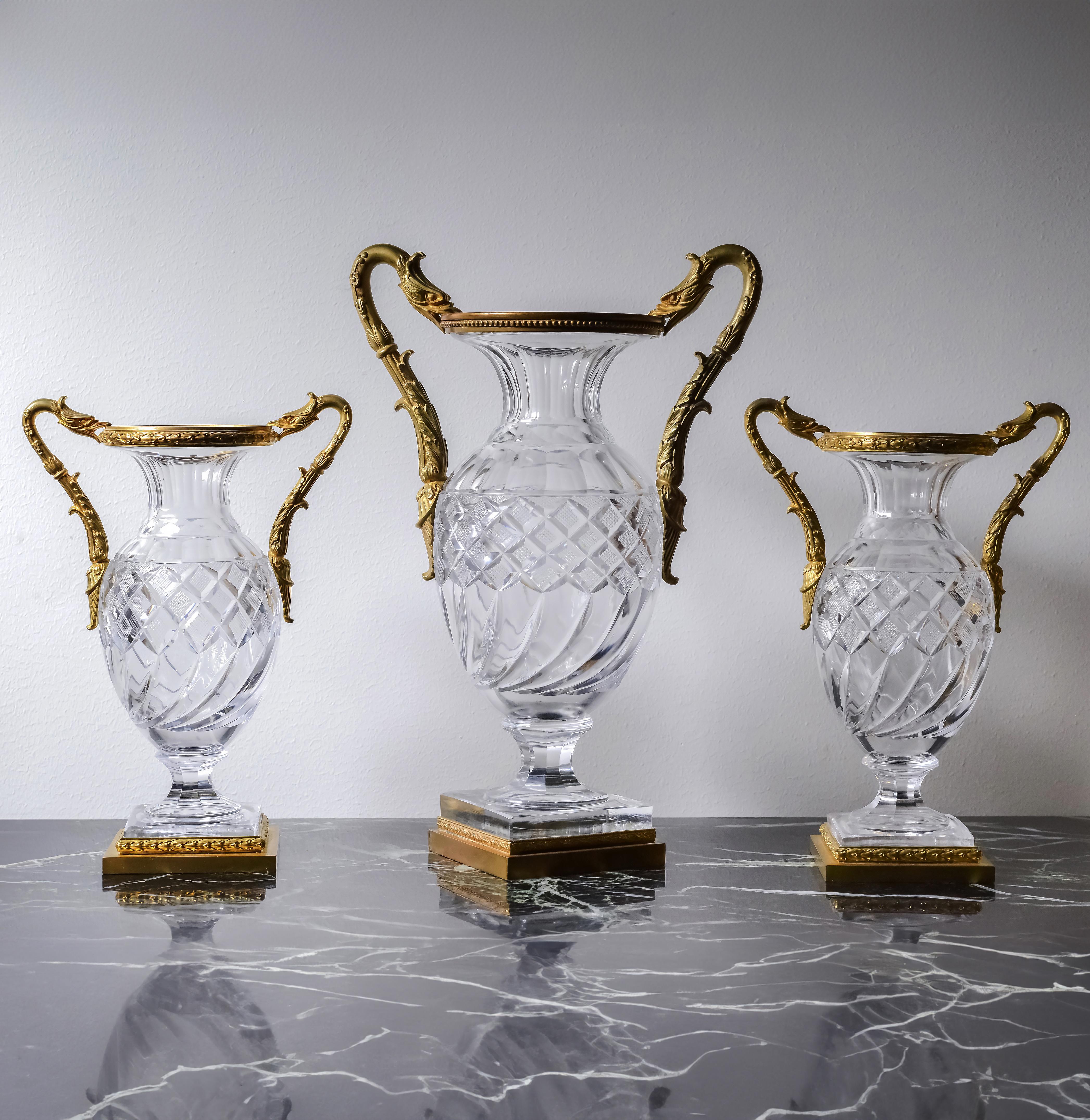 Rare verre en cristal de type Baccarat encadré de fines montures en bronze doré de feuillages à la base et de griffons stylisés en guise de poignées. A noter un motif asymétrique inhabituel sur le vase central. Il s'agit certainement d'un modèle de