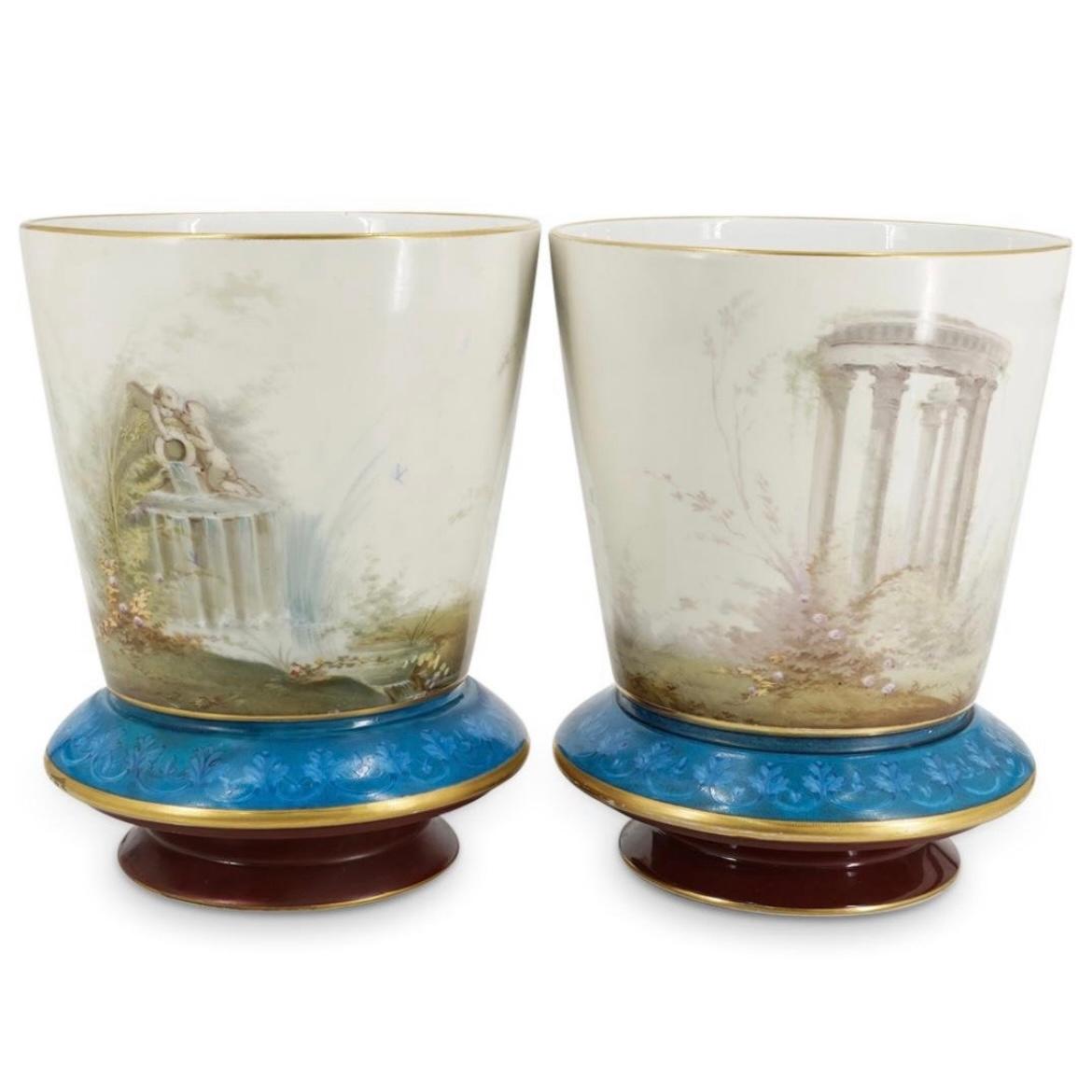 Nuestra excepcionalmente rara pareja de jardineras de opalina atribuidas a Baccarat se distinguen por su extenso esmaltado y sus diseños neoclásicos finamente pintados que incluyen doncellas con cupido, putti en una fuente y ruinas romanas, además