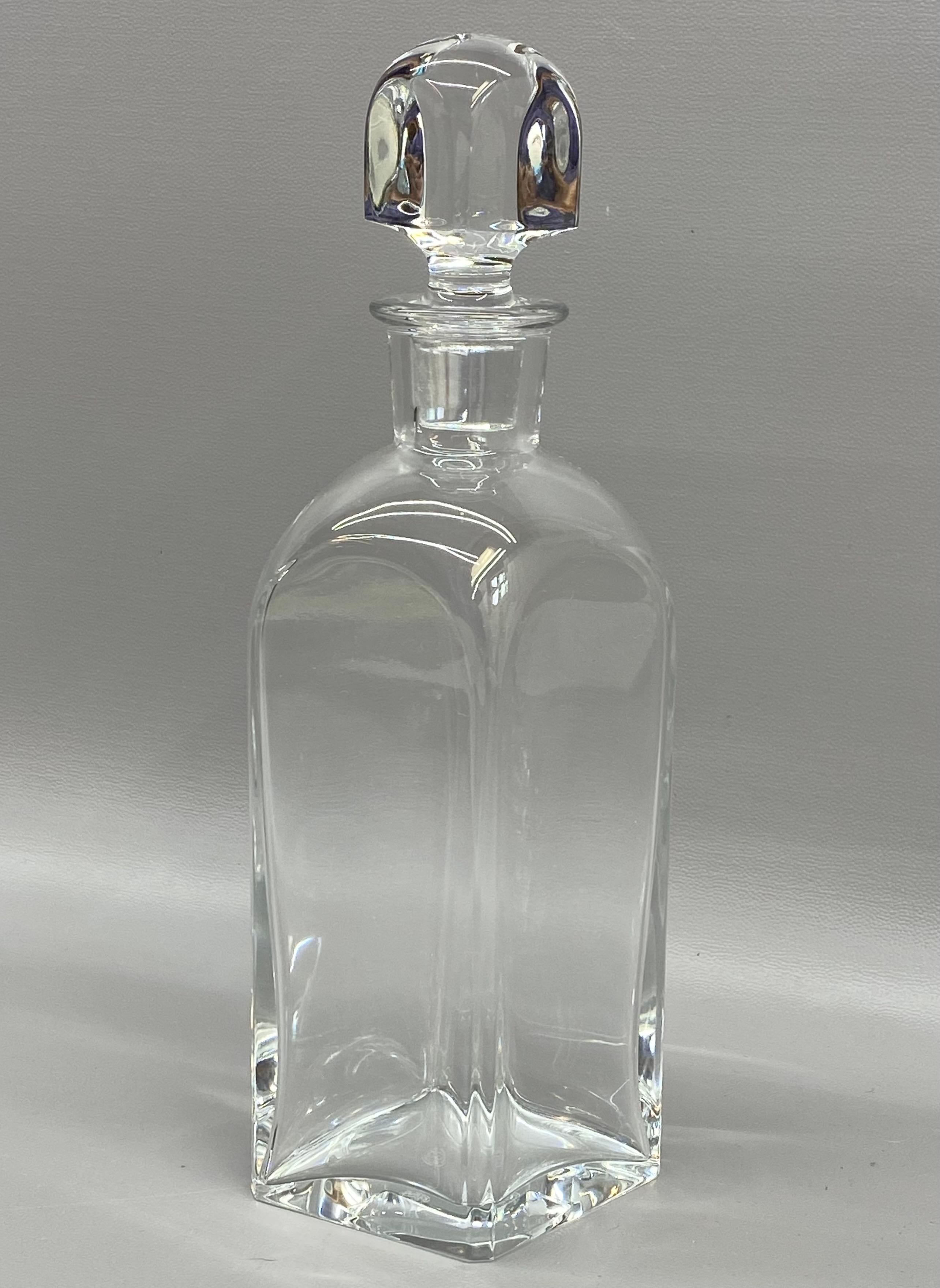 Bouteille en cristal français de Baccarat avec bouchon. Bouteille en cristal à facettes munie d'un bouchon arrondi et facetté. Circa 1980. Entièrement signé avec un tampon à l'acide sur le fond, Baccarat, France. Bon état général sans éclats,