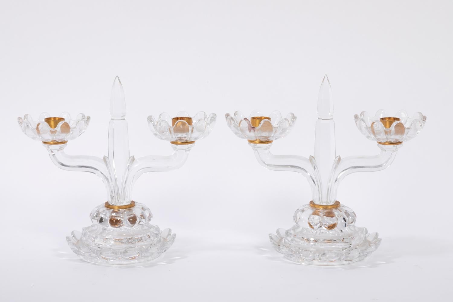 Baccarat, signed.

Pair of crystal candlesticks with two arms. Central shaft in dagger shape standing on a circular base with a gadroons decor and side with a wave shape, as the cups sides of the two arms. Bobeches and ring linking the shaft and