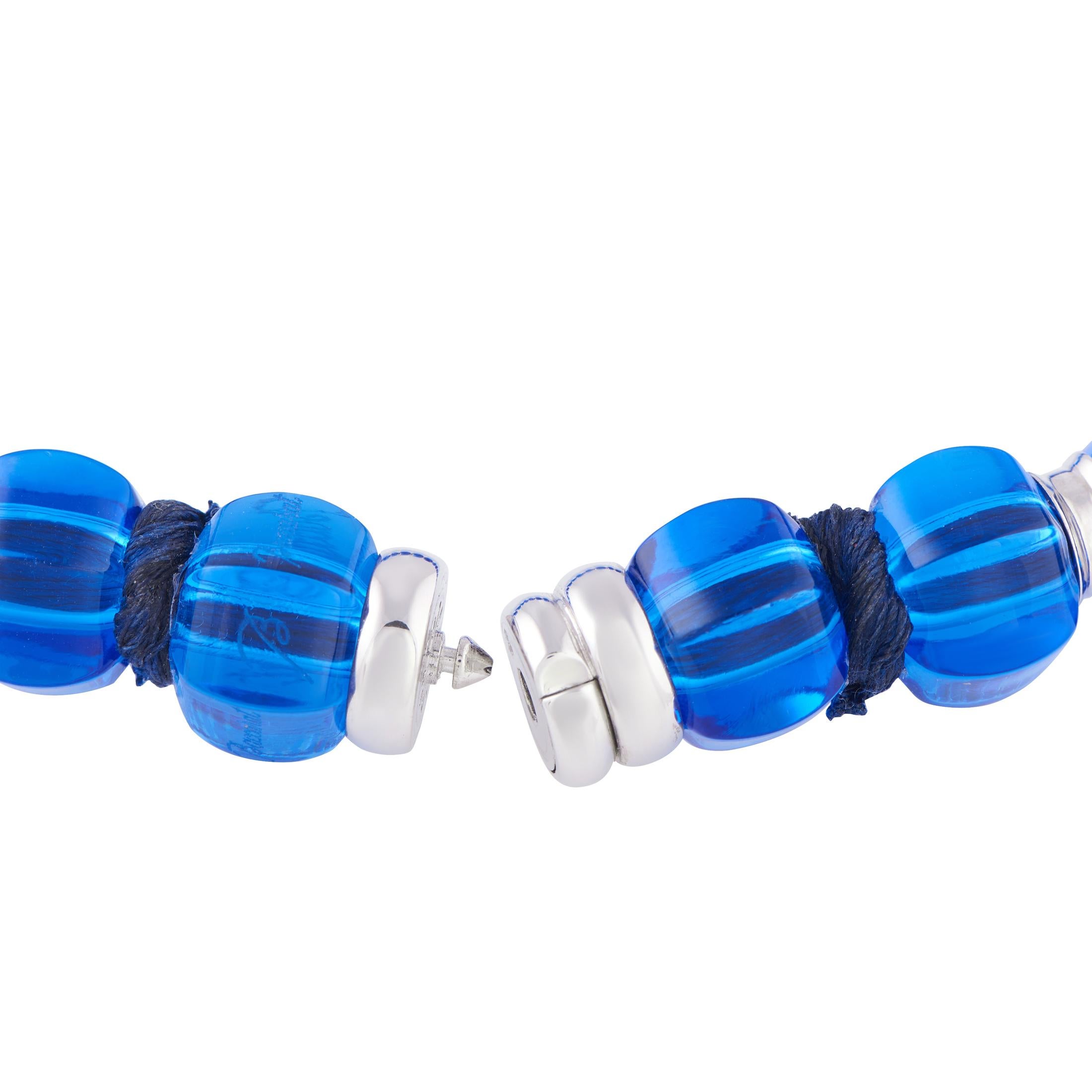 A bold and beautiful statement necklace from renowned crystal brand Baccarat. This piece features barrel-shaped blue crystals strung on a cotton rope. Between each crystal is a white gold rondelle spacer detailed with petite sapphires. Turn to this