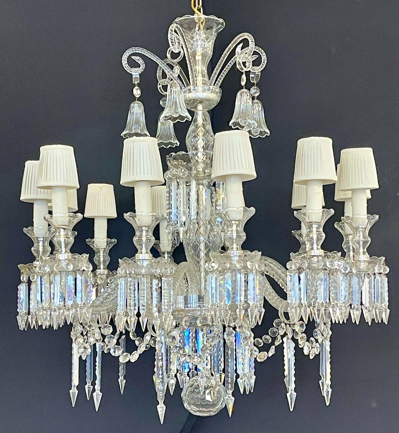 Baccarat style chandelier. A monumental crystal, 12 light chandelier having a center crystal column center with twelve lighted swag arms, terminating in crystal hooks each holding a crystal bell. 7feet of chain and a canopy are included. The larger