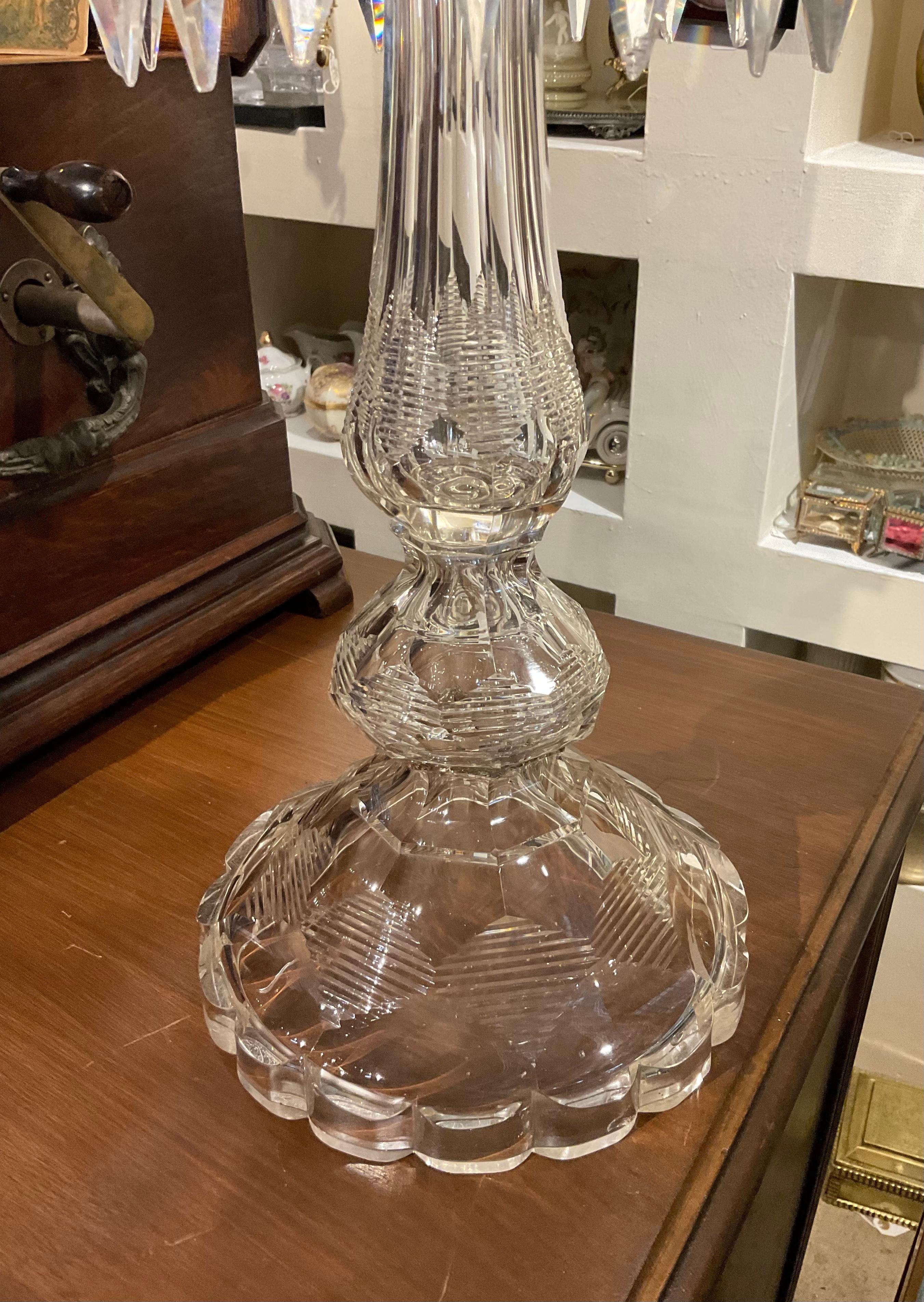 This is a Baccarat style high and large five arms crystal candelabra. It has five gold tone metal sconces with their white candles. It depicts a cut crystal high tulip shaped hurricane shades adorned with a bouquet of roses in the top and group of