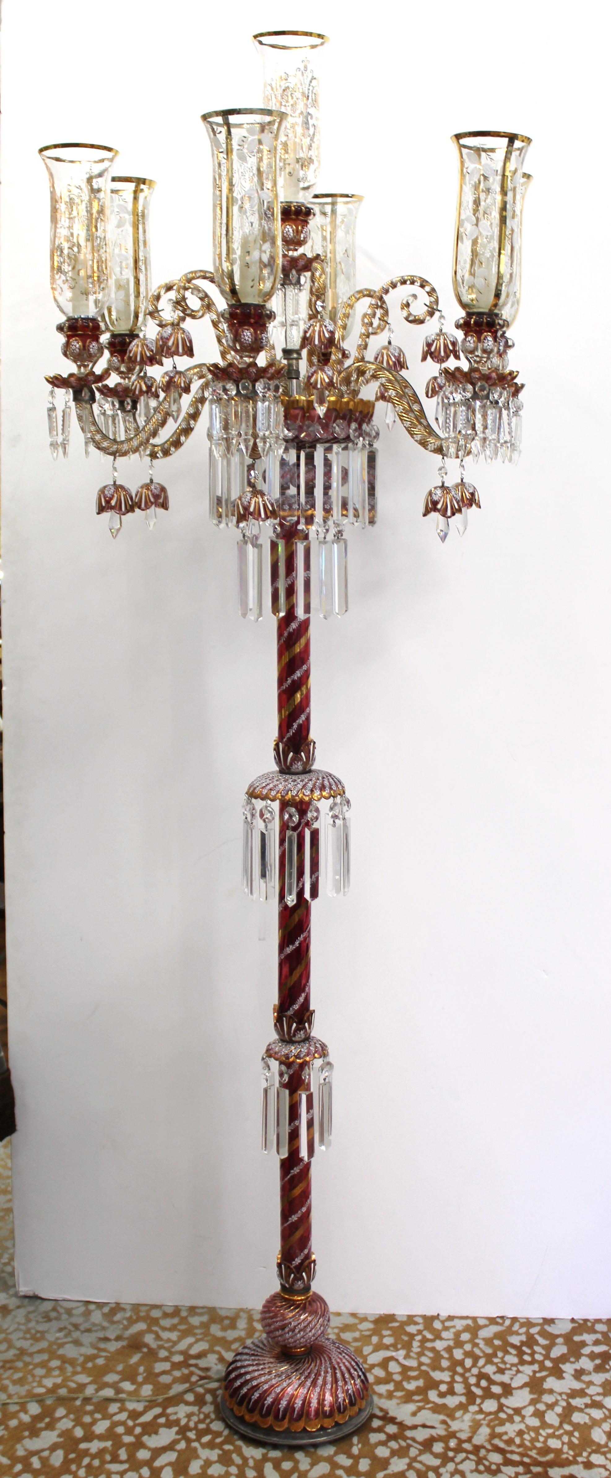 Victorian style pair of torchiere floor lamps designed in the style of Baccarat. The pair has crystal in a ruby finish and is decorated with enamel painted floral design and gilt elements as well as crystal drops. Each candle arm holds a decorated