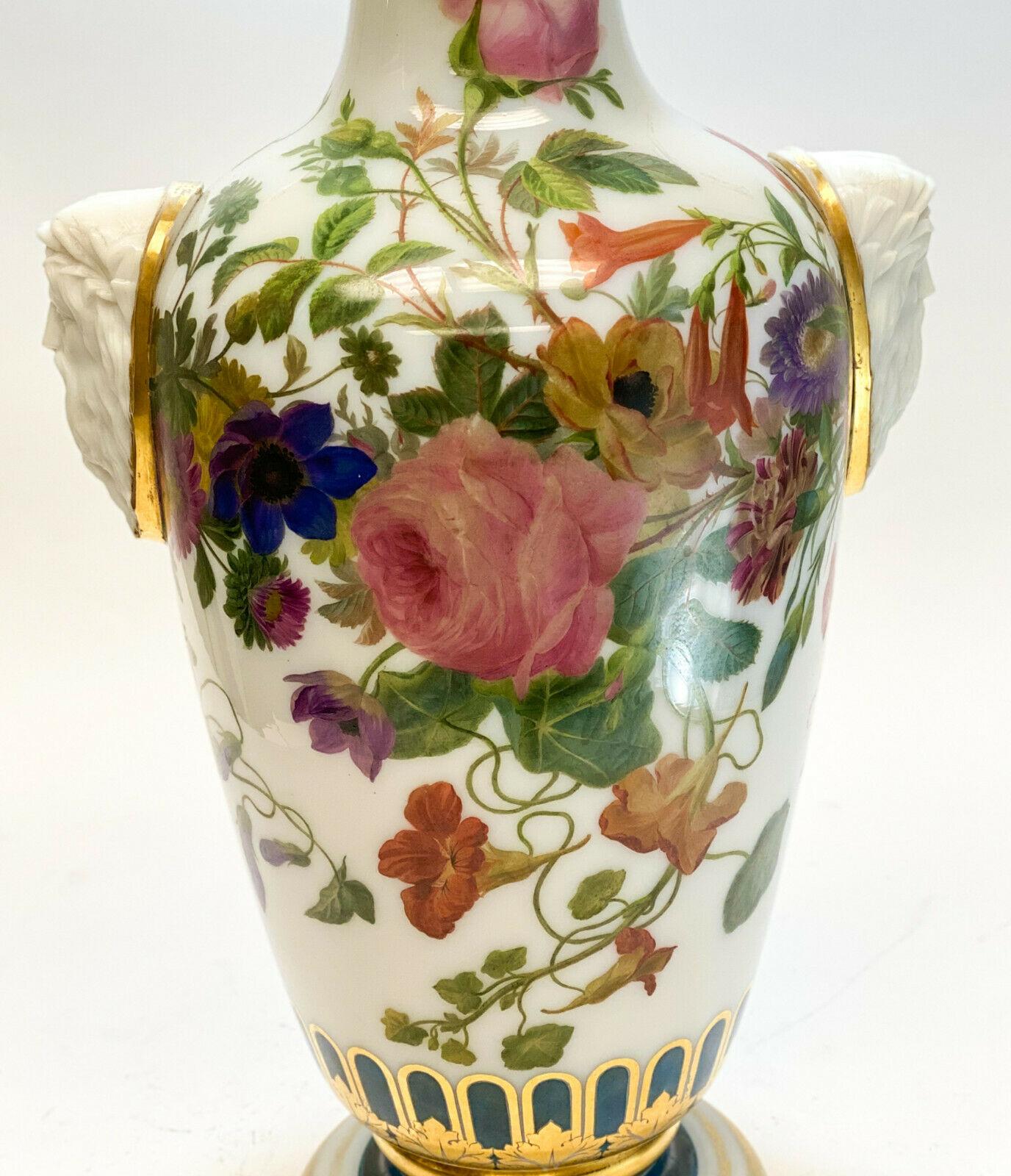 A large Baccarat white opaline hand painted vase, circa 1900. Beautiful multicolored hand painted florals throughout the vase with molded figural profile heads of a bearded man to the handles. Gilt accents to the top and base rim. 

Weight