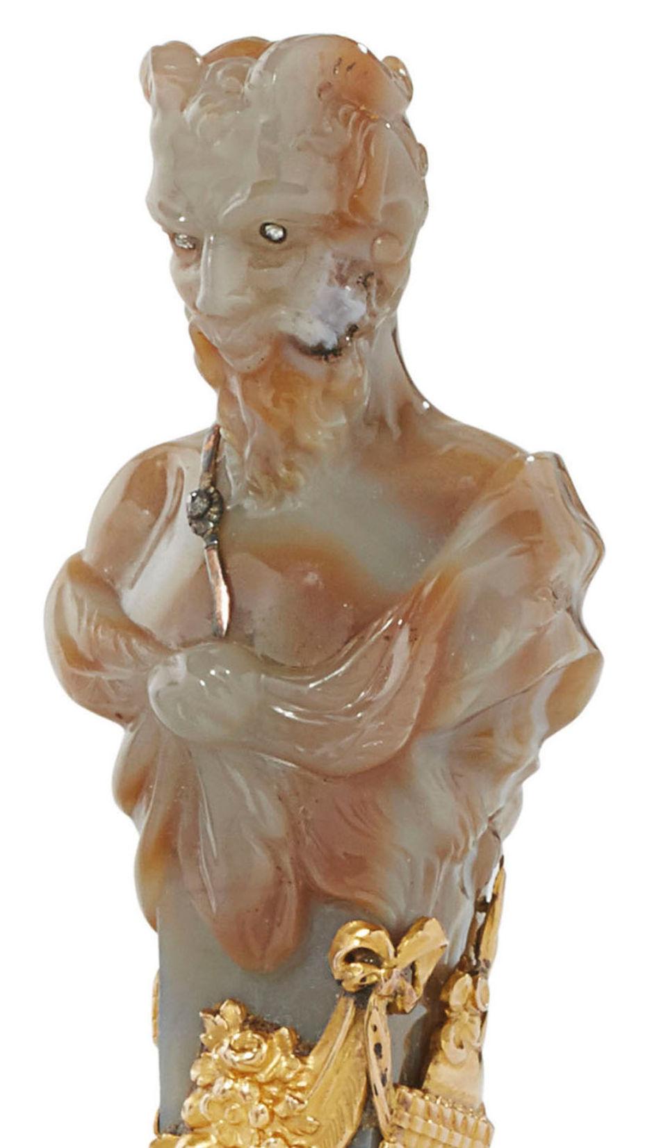 Our unusual seal carved from agate in the form of an herm-shaped Roman faun 
 features lovely gold overlay depicting accessories including sceptor, garland and flute, plus diamonds decorating the eyes and sash. Hinged at the base. Base is enameled