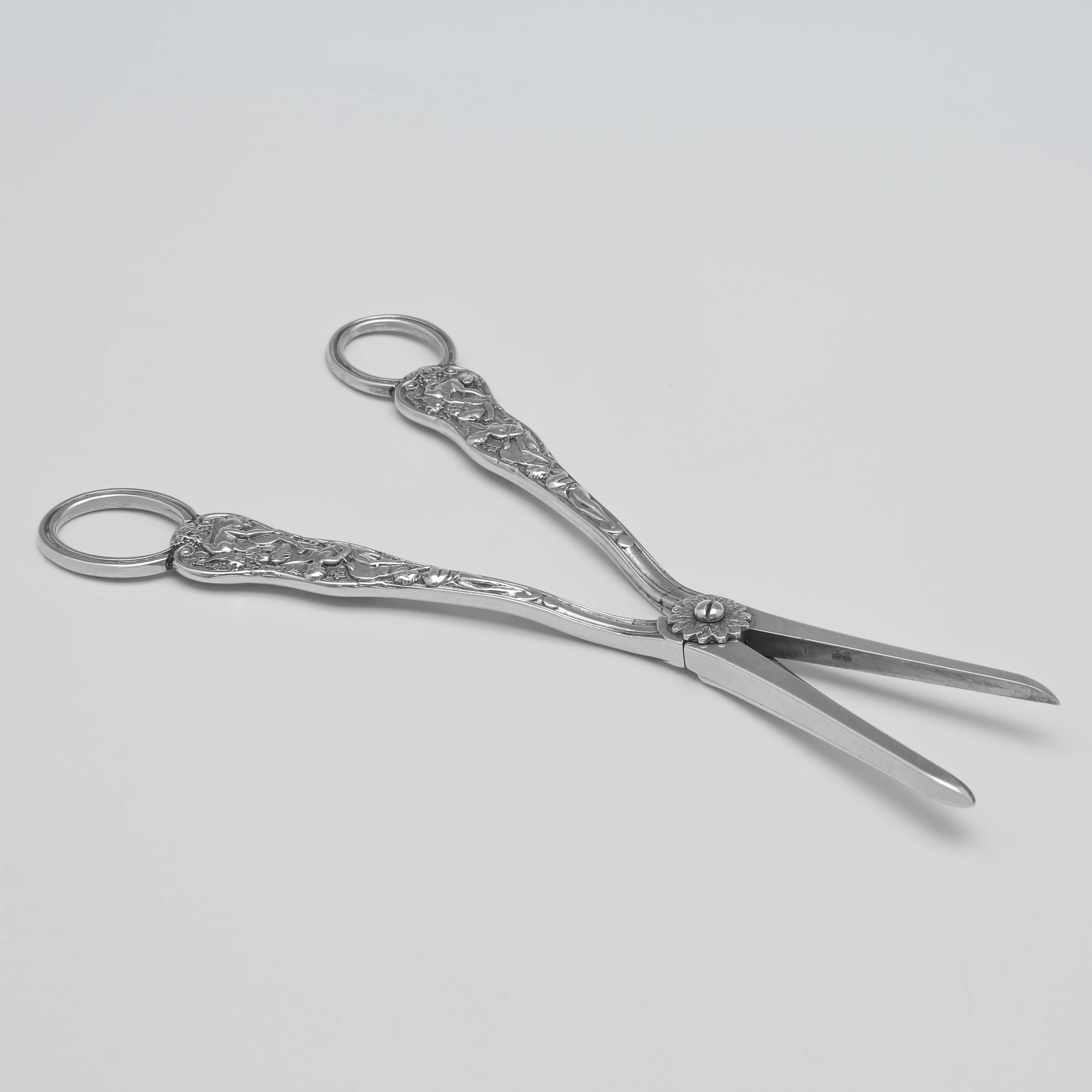 Hallmarked in London in 1874 by Henry John Lias & Son, this elaborate pair of Victorian, Antique Sterling Silver Grape Shears, are in 'Bacchanalian' pattern. The grape shears measure 7
