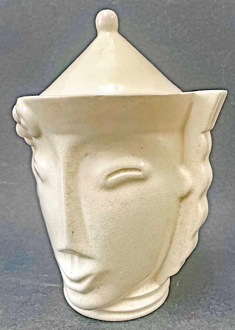 Striking and quintessentially Art Deco, this high-style face jar, enrobed in a pale ivory glaze, was designed by Madeleine Sougez for the famed Primavera ceramic workshop in the 1930s. Primavera was established by the famous Le Printemps department