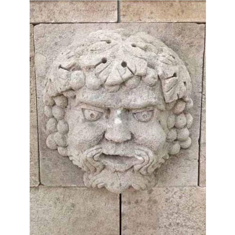 Here we offer a hand carved limestone wall fountain featuring the Roman god of wine Bacchus. The trim around the water exit, the crown atop the back and the curvature of the basin wall are all Classic French design that will add that touch of the