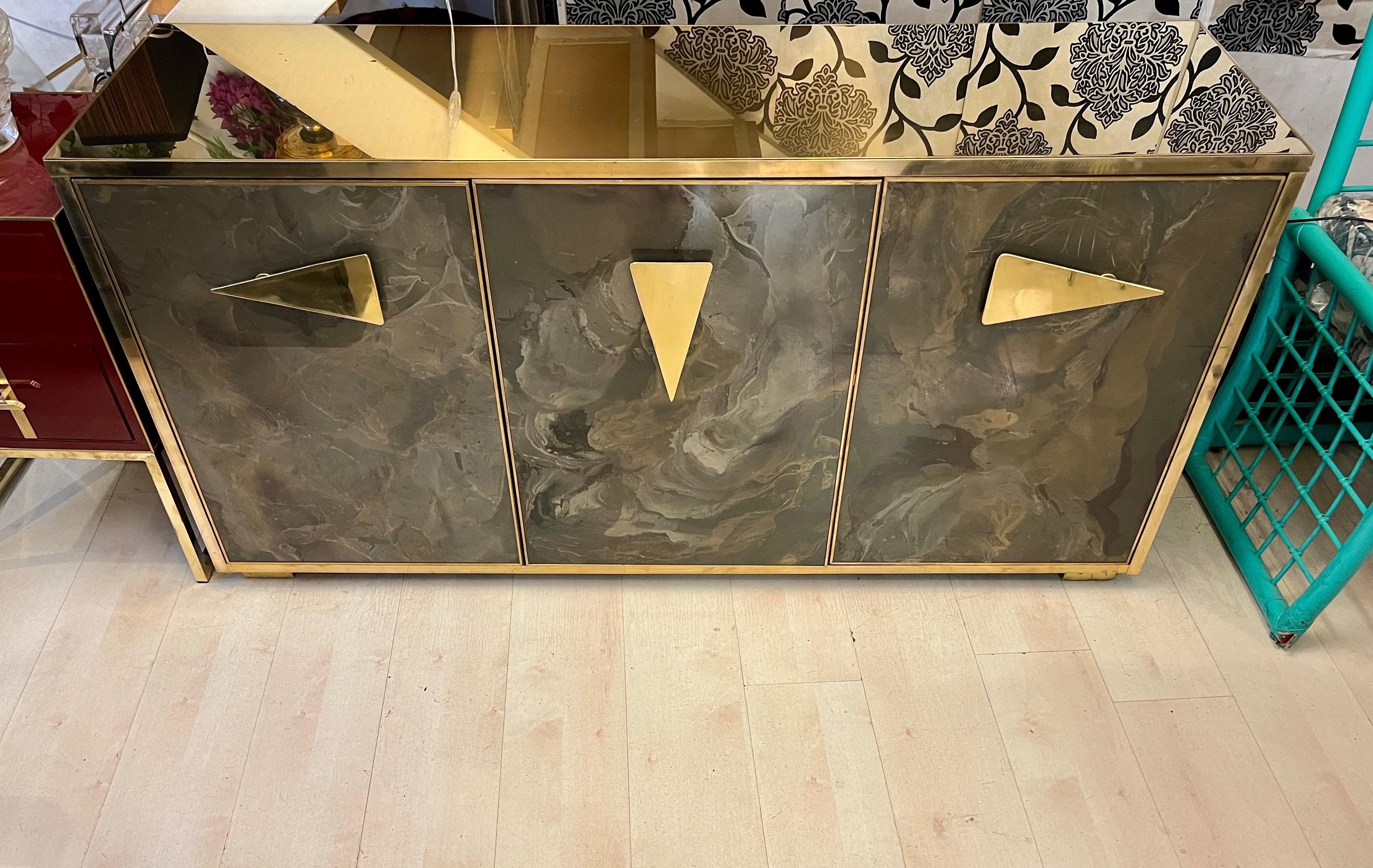 Aparador de cristal pintado a mano con tapa y marcos de latón. La decoración de efecto jaspeado está pintada a mano en la parte posterior del cristal, con tonos marrones, dorados y bronce. La parte superior de latón tiene un acabado dorado