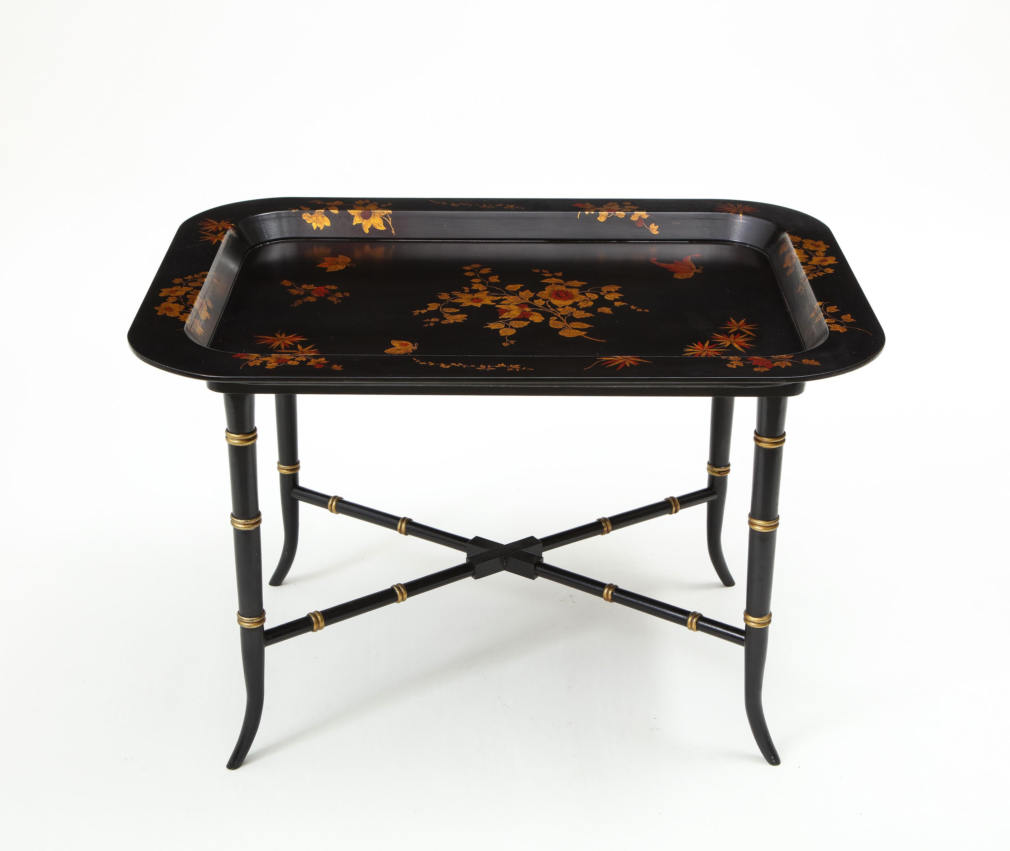 The rectangular dished removable tray decorated throughout with clumps of daffodils and butterflies. Raised on a later black and gilt painted based raised on bamboo-form sabre legs joined by an X-form stretcher.