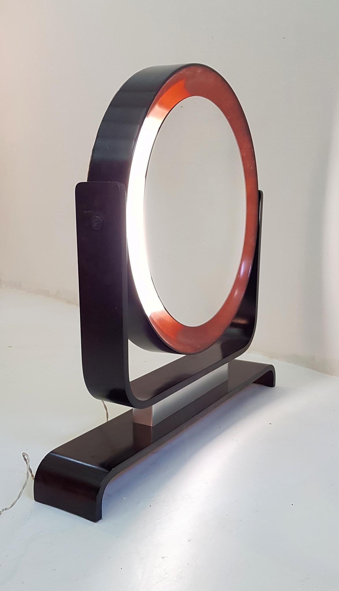 Un miroir de courtoisie rond en bois peint avec rétro-éclairage. Il est possible d'incliner le miroir. En bon état de fonctionnement.