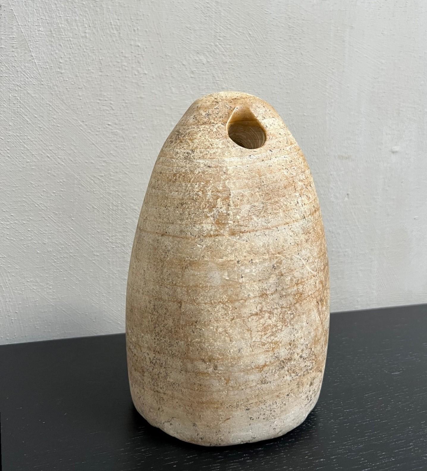A carved alabaster ovoid or aniconic idol with distinctive hole to the narrow end. 10.3 kg, 22cm (8 3/4
