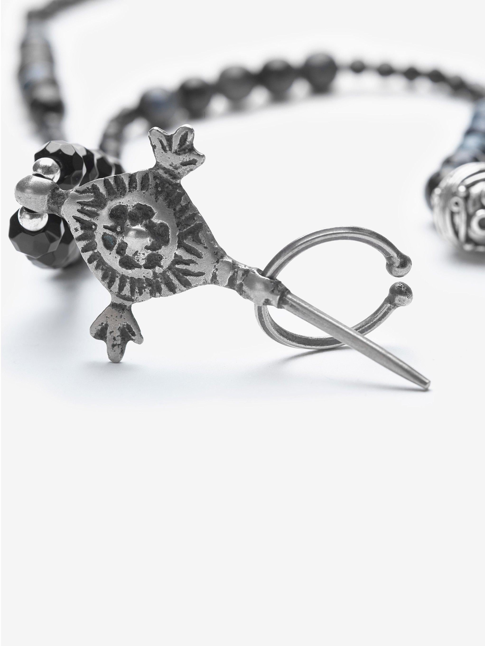 Die Geschichte des Schmucks 

Die wunderschöne Halskette ist mit Spinell und mitternachtsblauem Tigerauge geschmückt.  Der Anhänger wurde in den Souks von Fez, Marokko, gekauft. Das Symbol ist ein Kompass, ein wichtiges Symbol in der Berberkultur,