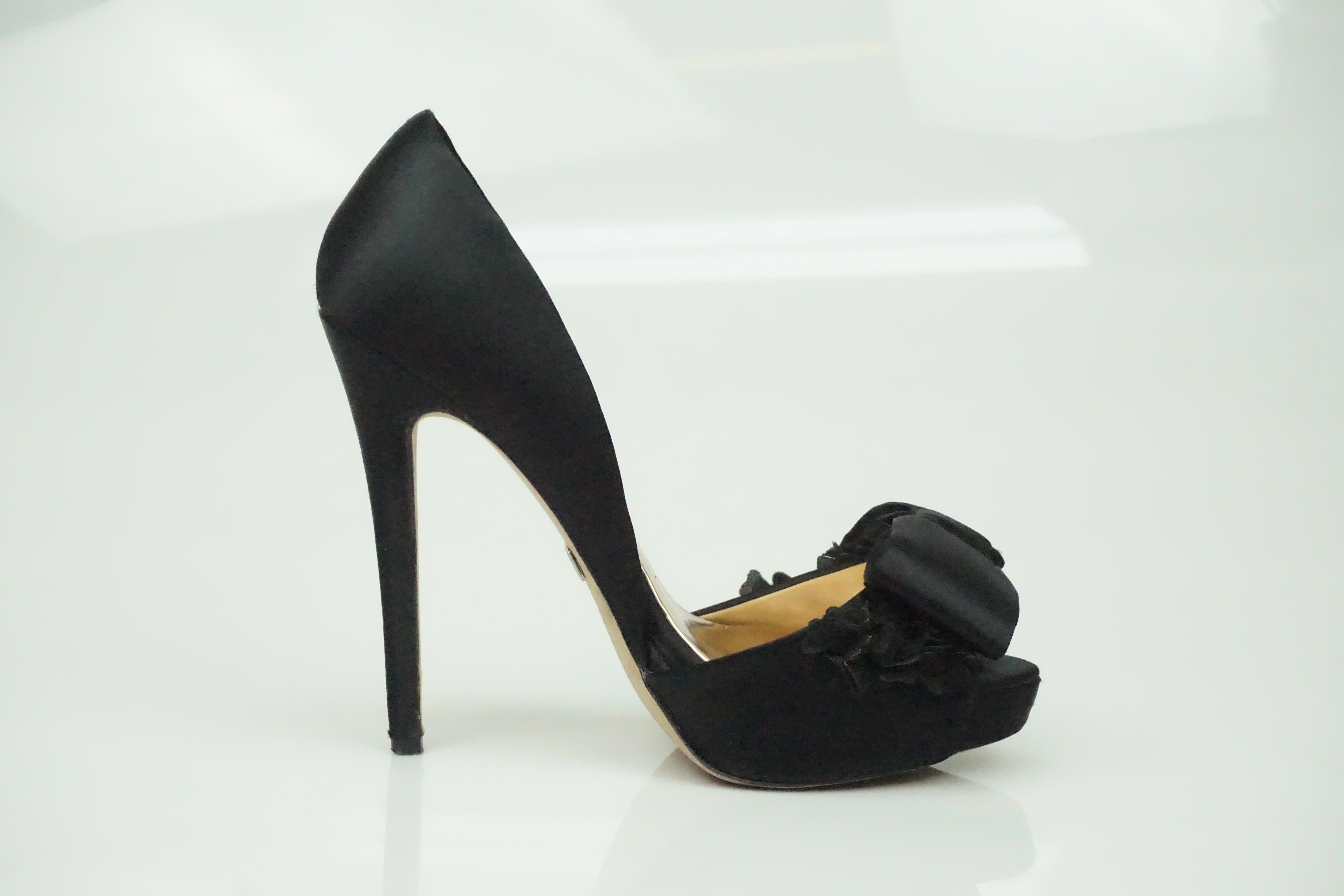 Badgley Mischka Schwarze Satin-Pump mit Blumen- und Schleifendetails   Diese schönen Schuhe sind in gutem Zustand. Sie haben eine metallisch anmutende Innenseite und eine Peep-Toe-Zehe. Die Oberseite des Schuhs hat eine schöne florale Details aus