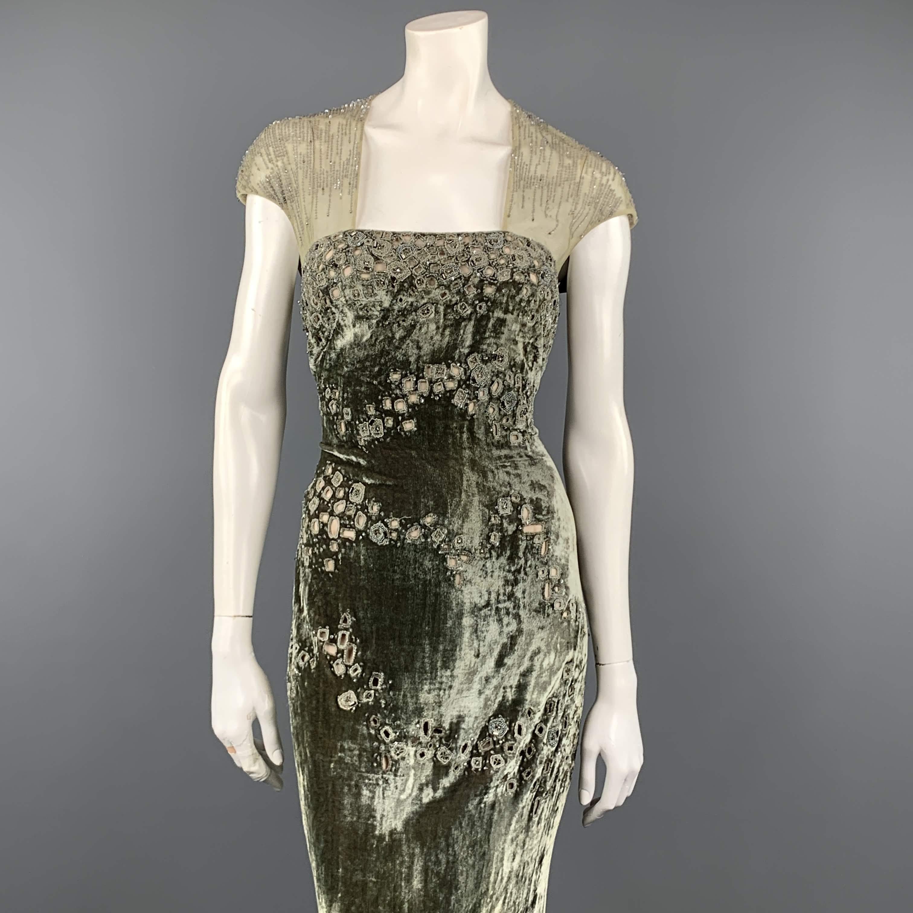 BADGLEY MISCHKA evening gown comes in moss green textured velvet with beaded cutouts throughout, a sheath silhouette body, beige chiffon liner, and beaded cap tulle cap sleeve top with button back. Tear in bottom of lining. As-is. Otherwise