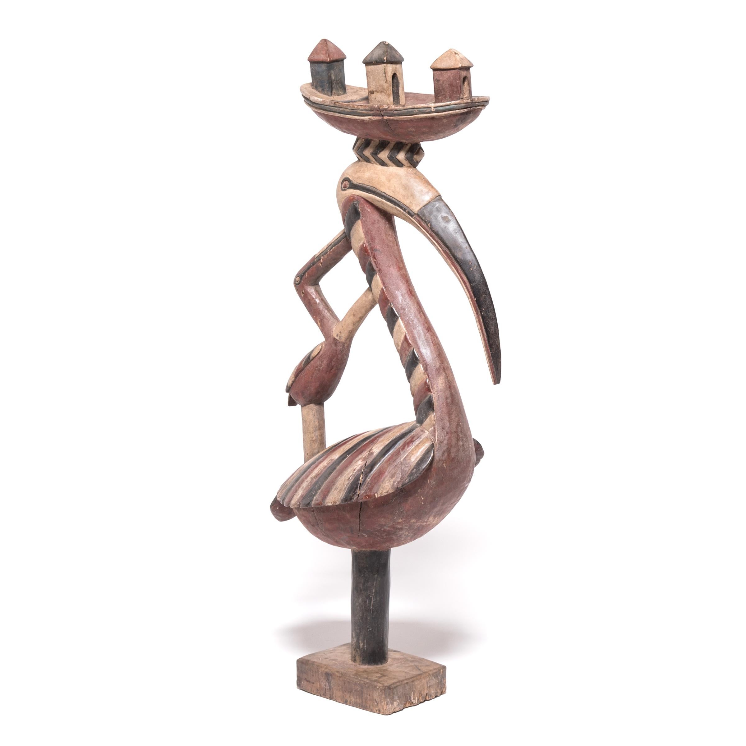 Questa graziosa scultura di un uccello dal collo lungo è un copricapo noto come 