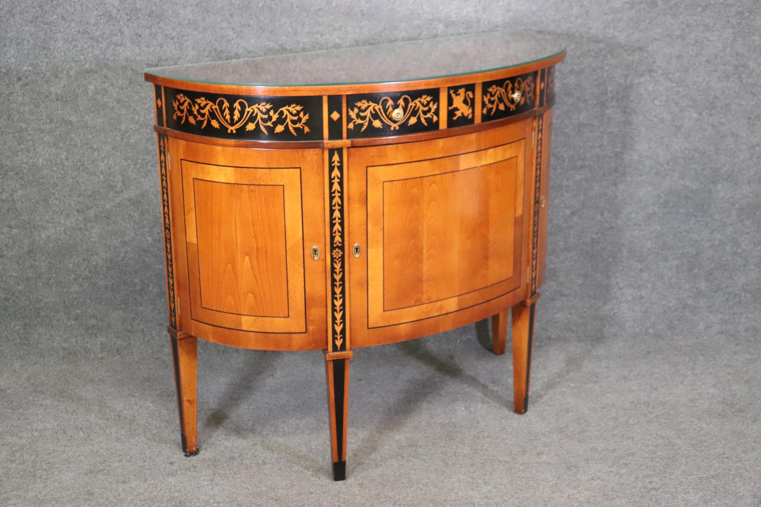 This is a Directoire style Italian-made by Baggio, demilune commode that has inlaid lions and foliage over a cherry case. The simplicity is beautiful and yet very warm and beautiful. The commode measures 44 wide x 37.5 tall x 18 deep and dates to
