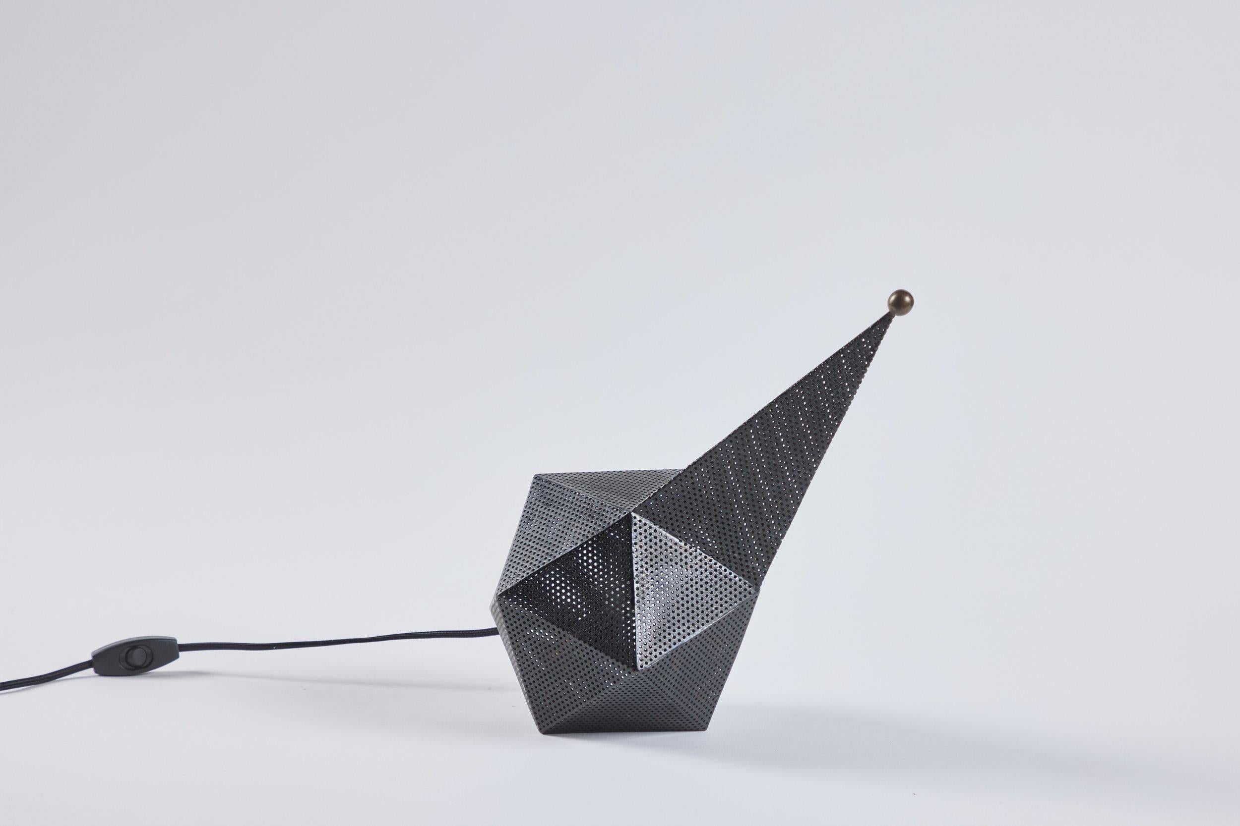  Lámpara de Bagdad de Mathieu Mategot. La pieza tiene una forma escultórica única compuesta por series de ángulos no lineales y está construida en metal perforado que permite la transparencia de la luz. La pieza está rematada con un remate de bola