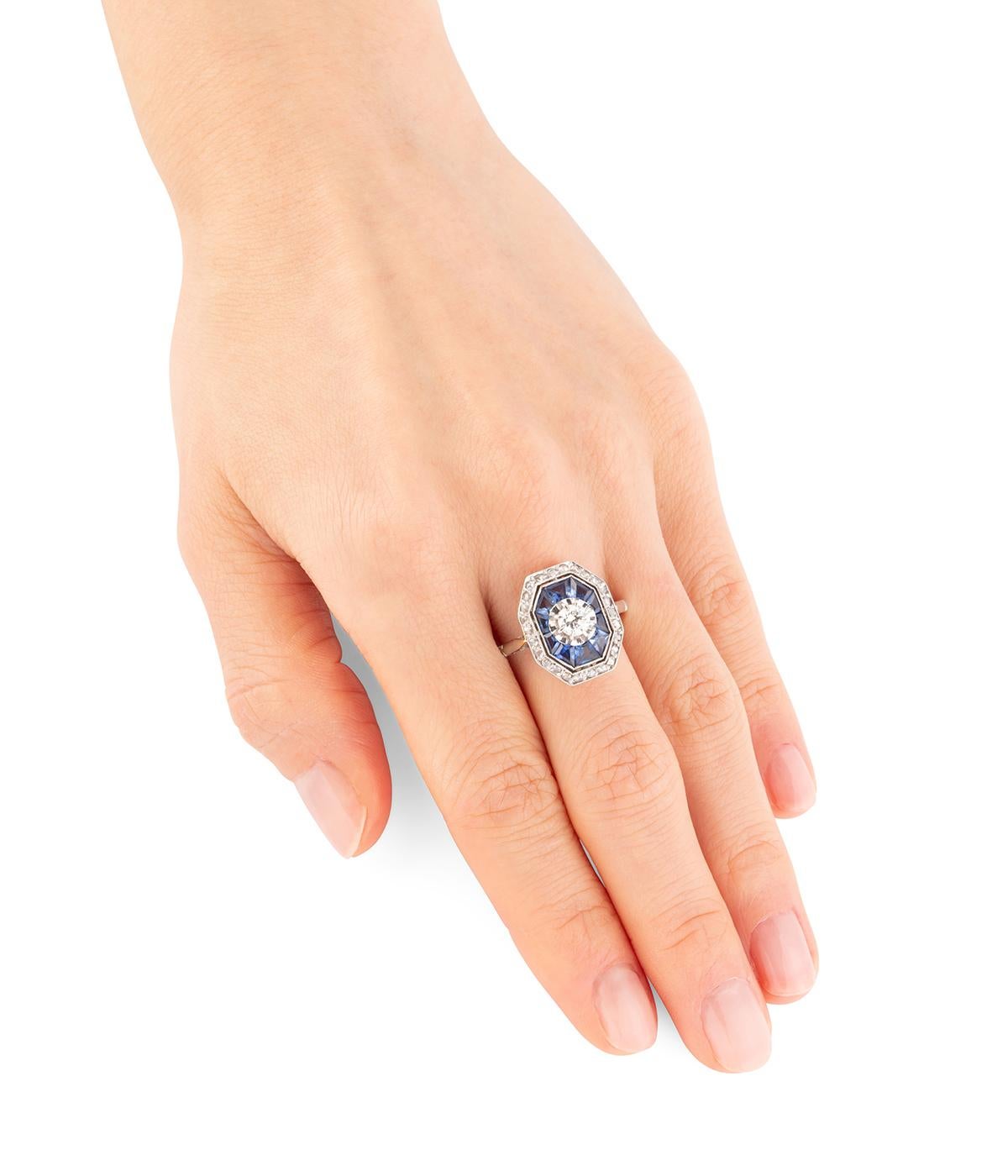 Bague Art déco en or 18 carats (750 millièmes) et platine. Elle est centrée d'un diamant taille ancienne d'env.  0,35 carats, entouré de saphir calibrés et d'une ligne de diamants taille rose.

Poids total du bijou : 3,5 g environ.
Taille