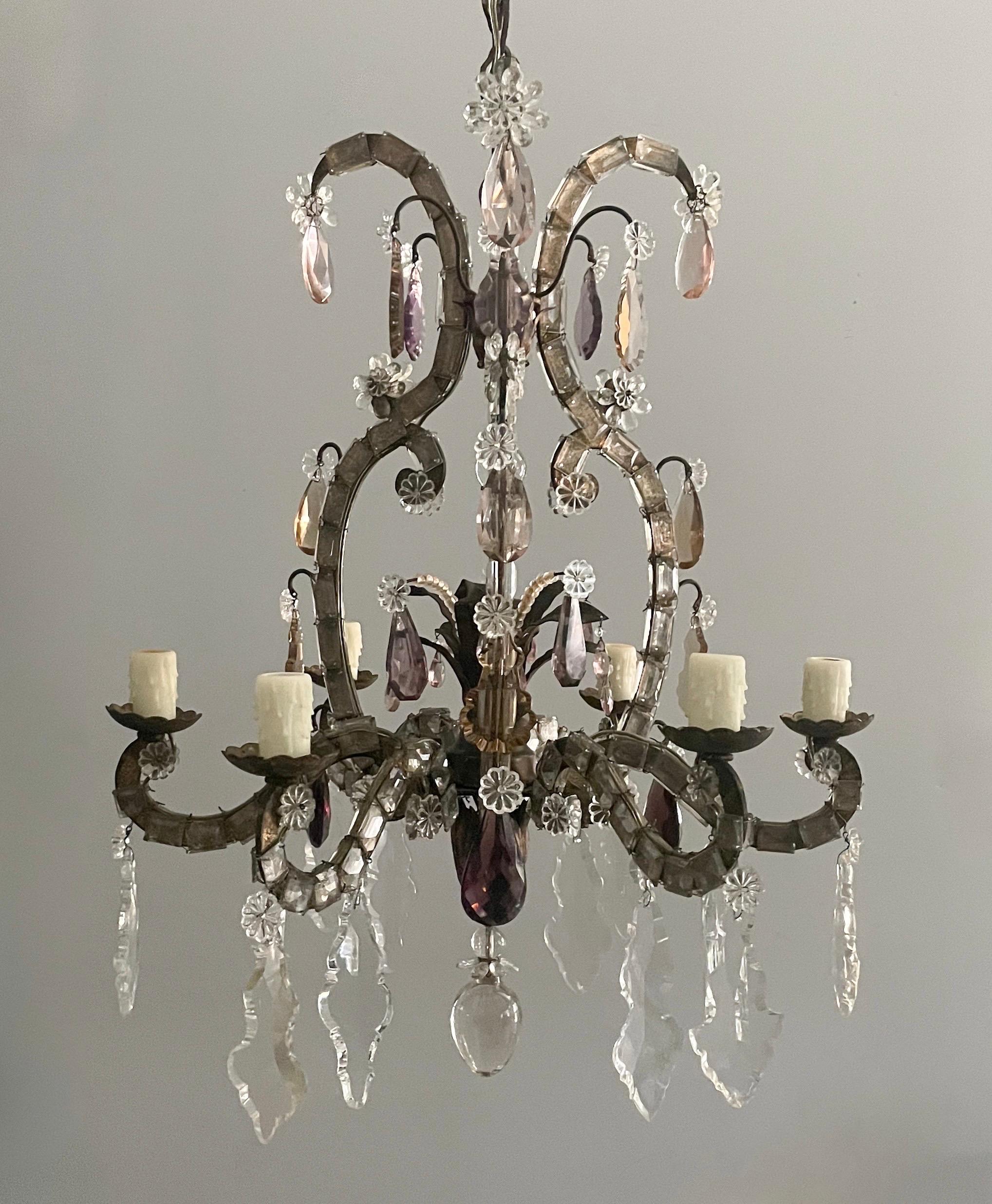 An exquisite, 1920s French gilt-iron and crystal beaded chandelier in the manner of Maison Baguès.

The chandelier features a scrolled-iron frame with a naturally distressed gilt-finish. Faceted square and rectangular prisms outline the chandelier’s