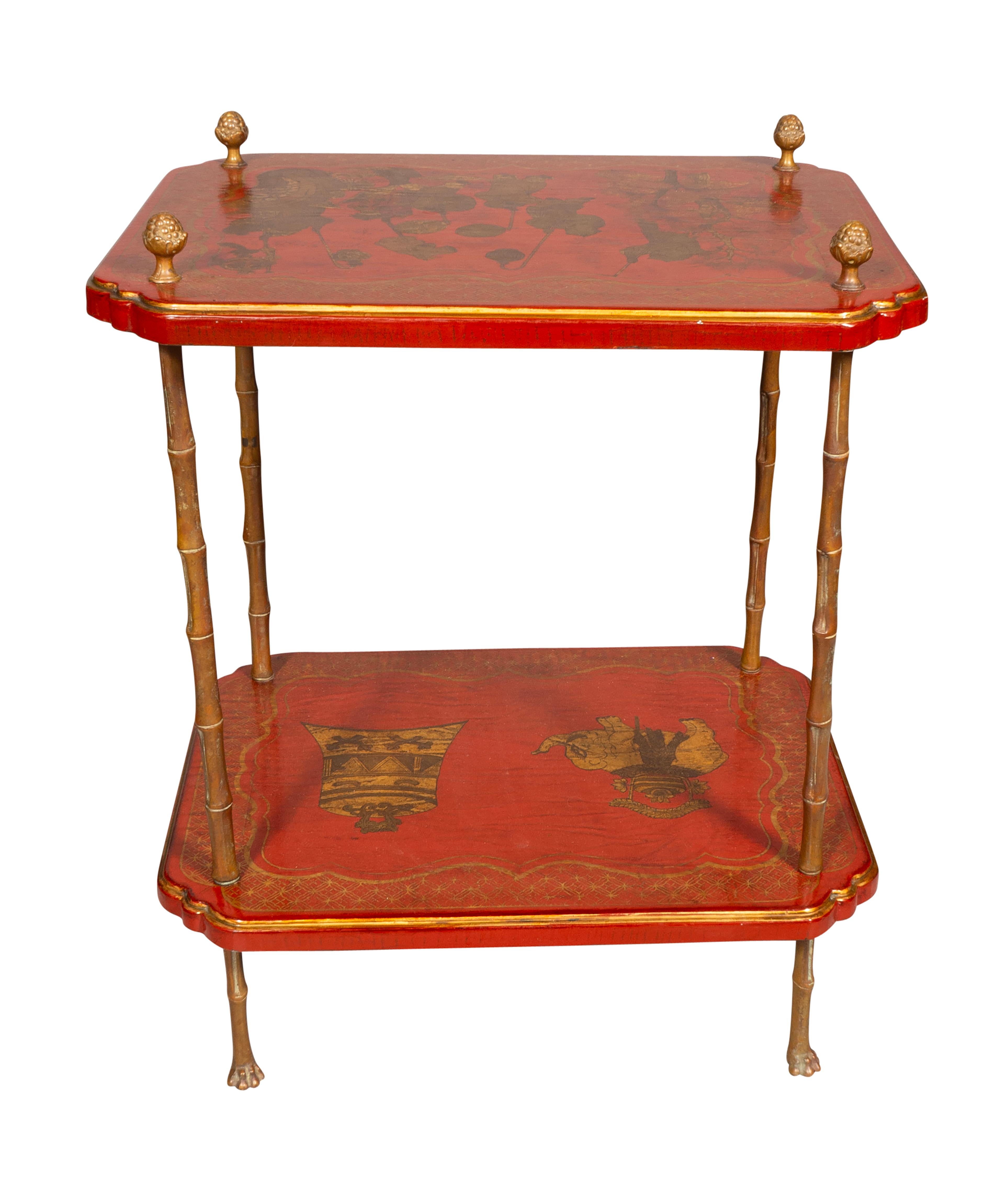Red japanned and gilt details with two tiers and with brass shelf dividers and legs.